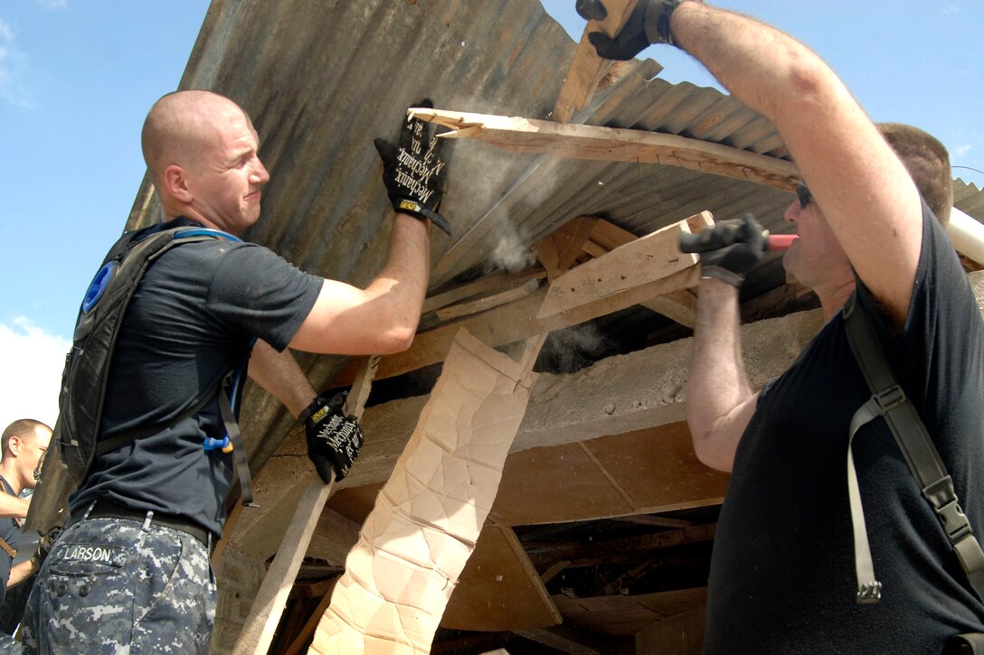 U.S. Navy Petty Officer 2nd Class David Larson, left, and Senior Chief Jeremy Fleming repair a damaged roof on a building on Gonave Island, Haiti, Jan. 27, 2010. The sailors are assigned to the USS Fort McHenry.