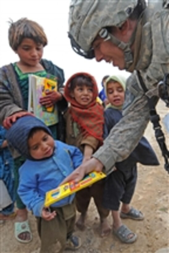 U.S. Army Staff Sgt. Paul D. Ballesteros, with Bear Troop, 8th Squadron, 1st Cavalry Regiment, passes out colored pencils to Afghan children during a population engagement in a village in Kandahar province, Afghanistan, on Jan. 28, 2010.  