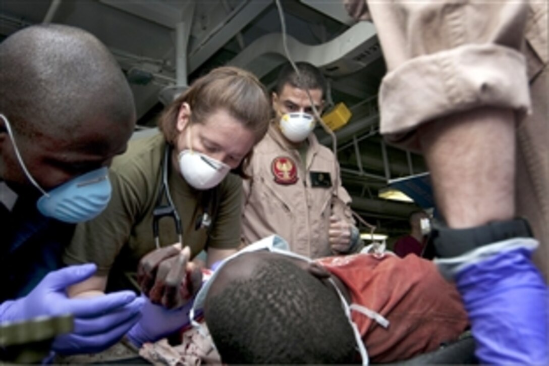 U.S. Navy Lt. Jamie Fitch, Petty Officer 3rd Class Alejandro Calzada and Petty Officer 3rd Class Dodji Kouchi provide medical assistance to evacuees from Haiti aboard the amphibious assault ship USS Nassau, Jan. 25, 2010. The Nassau is supporting Operation Unified Response following a devastating earthquake to the island naiton. Calzada is a hospital corpsman and Kouchi is a logistics specialist.