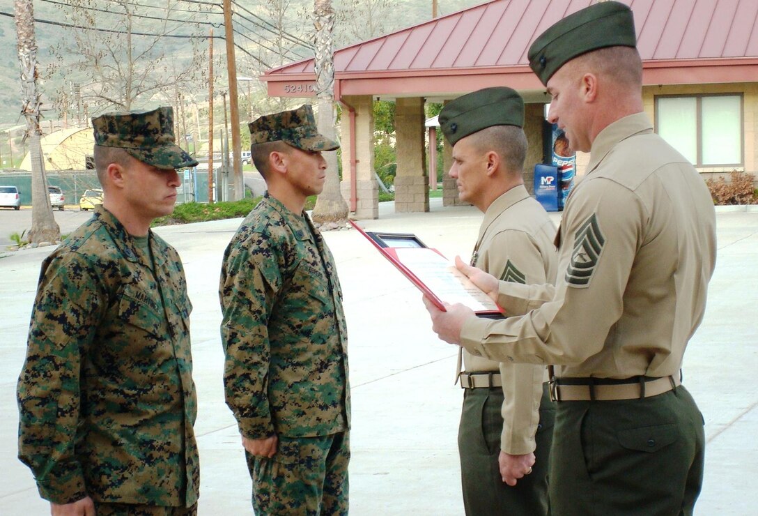 Master Sgt. John Stefan, senior faculty advisor, Staff Noncommissioned Officer Academy, Camp Pendleton assists Sgt. Maj. Robert A. Ledferd, director, Staff NCO Academy, Marine Corps Base Camp Pendleton as they recognize they newly appointed faculty advisors, (right) Staff Sgt. Anthony Obrero and (left) Gunnery Sgt. Michael Martinet during an award ceremony, Feb.1. The mandated course seeks to modernize the academy’s approach of teaching helps to preserve a genuine, career-long bond between teachers, known as faculty advisors, and students attending the academy.::r::::n::