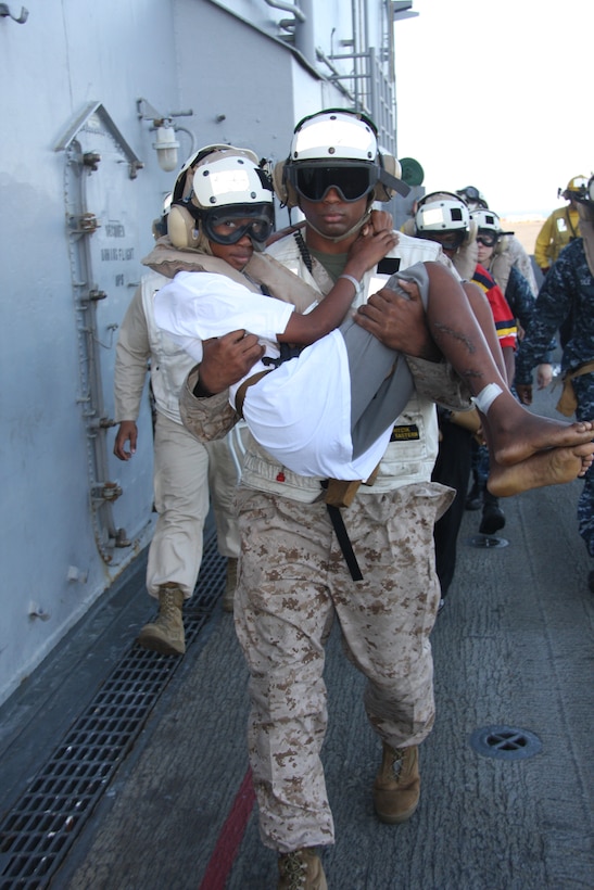 Sgt. Jarrell Williams, platoon sergeant, Combat Cargo, 24th Marine Expeditionary Unit, carries 14-year-old Lydie Augustin across the flight deck aboard USS Nassau and into a Marine Medium Tilt Rotor Squadron 162 (Reinforced) MV-22 Osprey in which she was flown back to her village of Grande Saliene, Haiti, to be reunited with her family and friends, Feb. 1. Lydie was brought aboard USS Nassau a week prior in order to receive emergency medical care of her wounds which she received during the devastating earthquake in Haiti, Jan. 12.