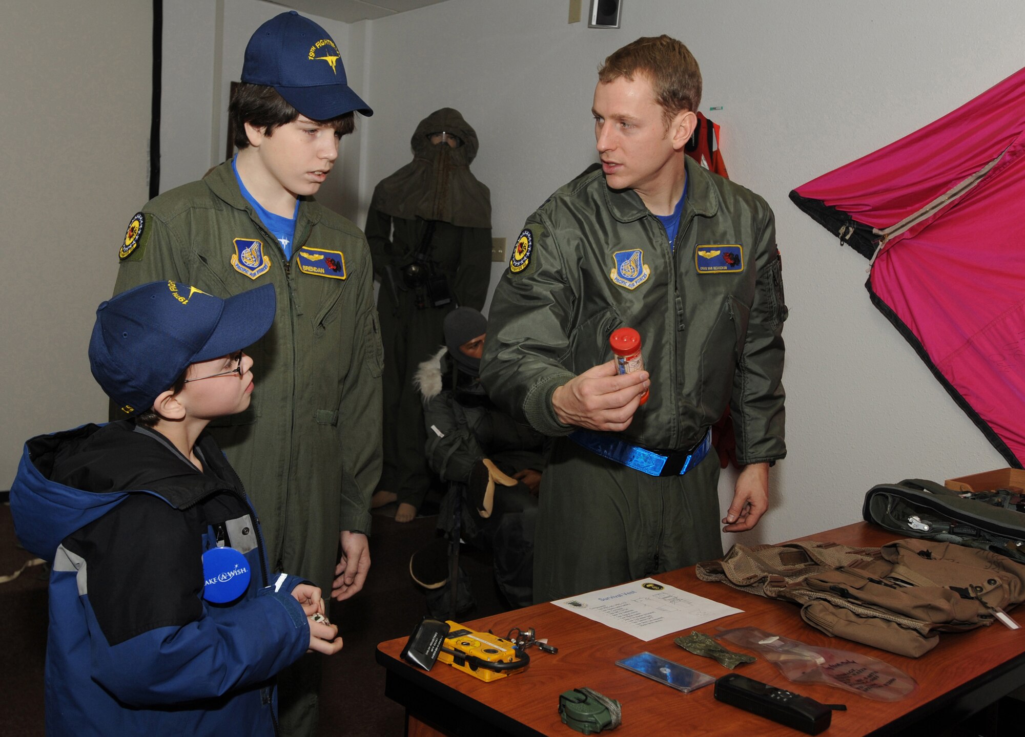 ELMENDORF AIR FORCE BASE, Alaska -- Capt. Craig Van Beusekom explains the survival equipment 19th Fighter Squadron F-15 pilots carry with them to ensure survival and rescue to Brendan Thompson, 19 FS's Pilot for a Day and Make-A-Wish recipient, and his brother Joshua Jan 29. Brendan was diagnosed with Aplastic Anemia, a rare bone marrow cancer, and is currently receiving treatment. (U.S. Air Force photo/ Airman 1st Class Kristin High)