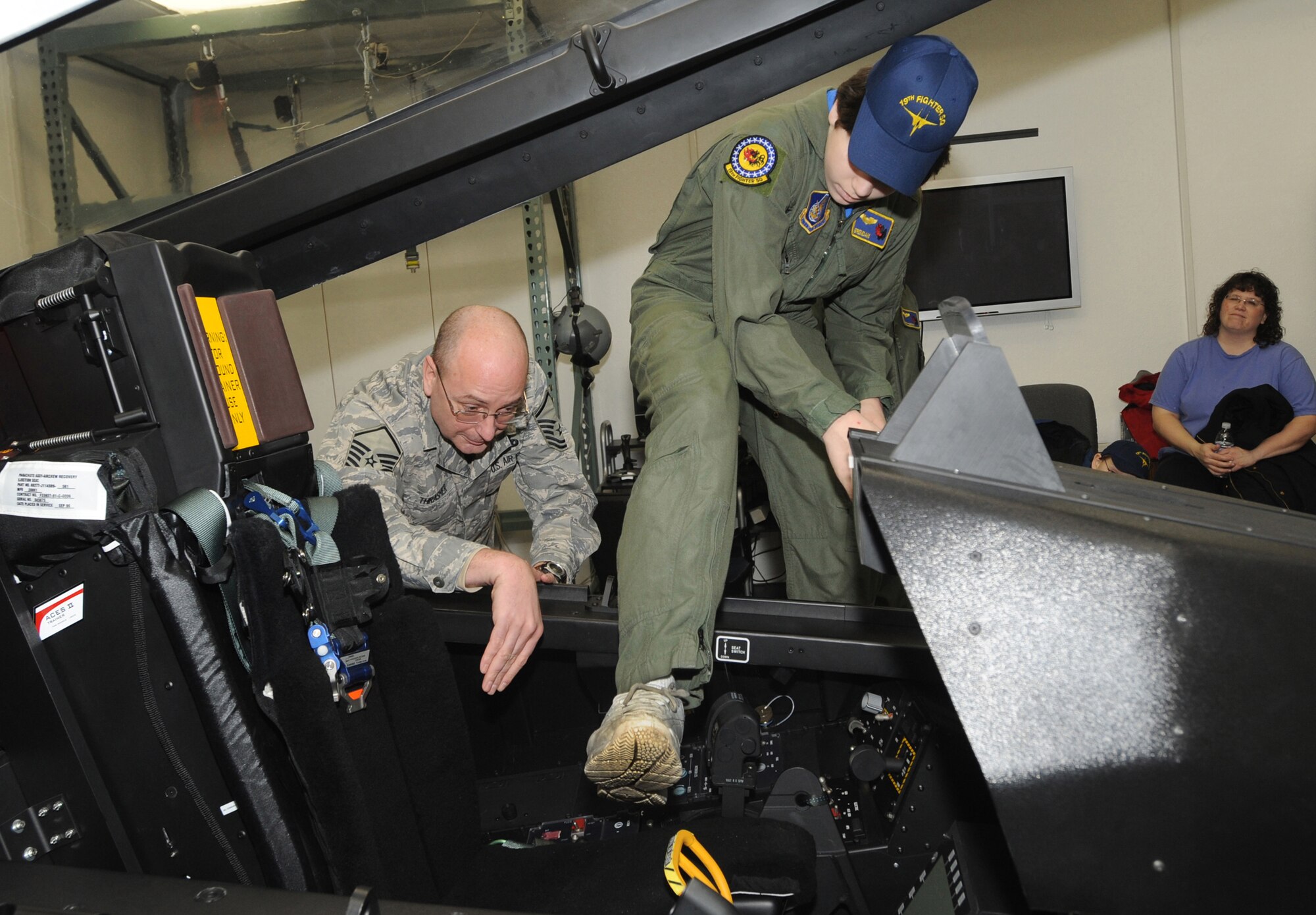 ELMENDORF AIR FORCE BASE, Alaska -- Master Sgt. Patrick Thrasher, 3rd Operations Support Squadron helps Brendan Thompson, 19th FS's pilot for a Day and Make-A-Wish recipient, climb into the F-22 egress trainer at the 3 Wing Aerospace Flight Equipment Building Jan 29. Brendan was diagnosed with Aplastic Anemia, a rare bone marrow cancer, and is currently receiving treatment. (U.S. Air Force photo/ Airman 1st Class Kristin High)