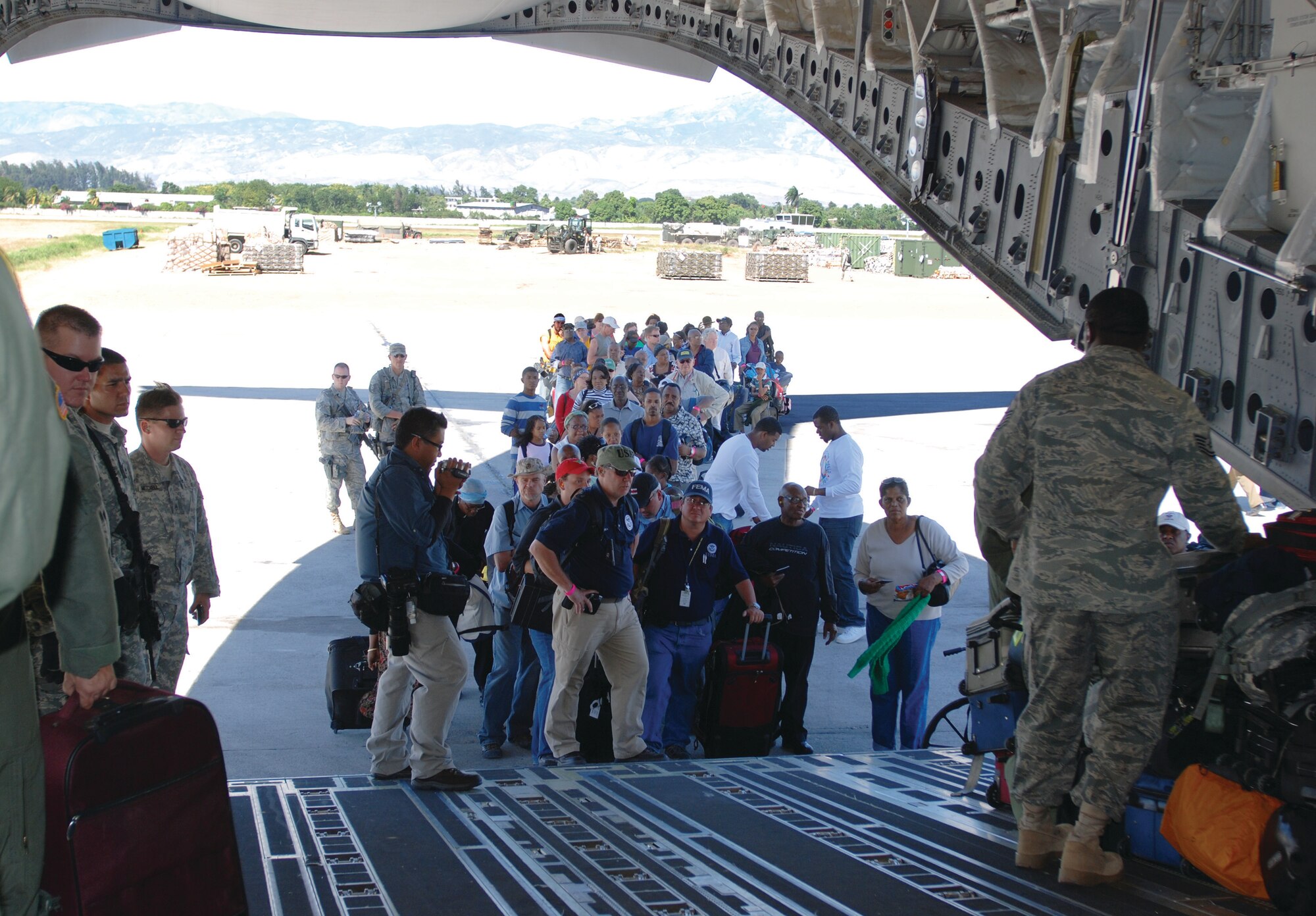 Aid workers and evacuees with U.S. passports and visas wait in line to board a C-17 Globemaster III from March Air Reserve Base in Port-au-Prince, Haiti, Jan. 29. The C-17 flew three missions as part of Operation UNIFIED RESPONSE into Haiti, before returning to March ARB, Feb. 1.  (U.S. Air Force Photo/Capt. Ashley Norris)