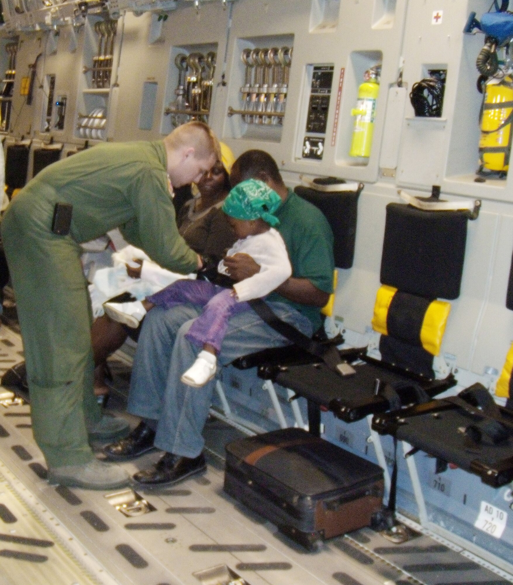 Airman 1st Class Landon Greenwood helps buckle in a young girl being evacuated on a C-17 Globemaster III to the U.S. Jan. 19, 2010, from Port-au-Prince, Haiti. The C-17 aircrew had delivered 90,000 pounds of cargo and was boarding 36 evacuees in support of Operation Unified Response. Airman Greenwood is a loadmaster with the 3rd Airlift Squadron at Dover Air Force Base, Del. (U.S. Air Force photo/2nd Lt. Abigail Wise)