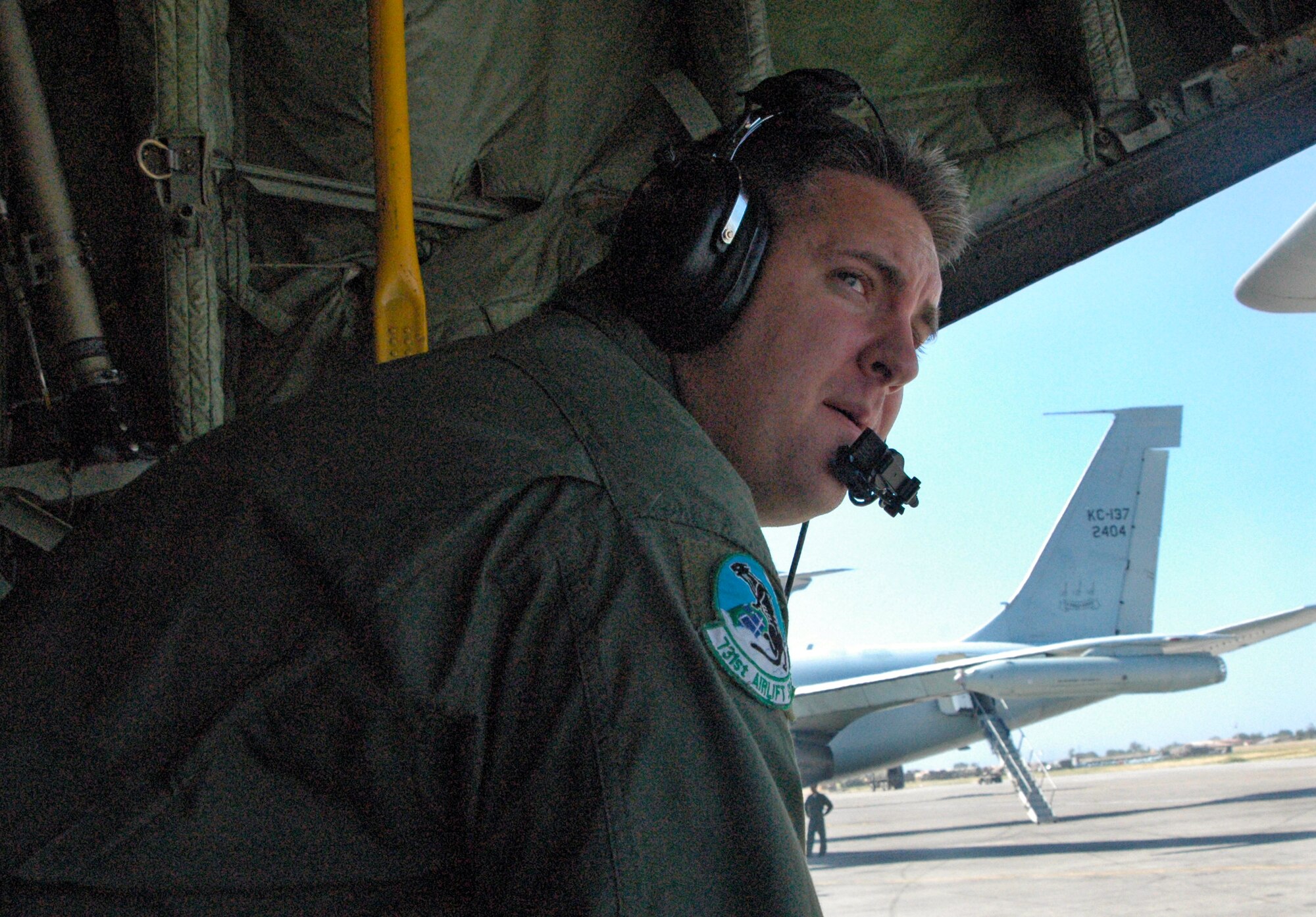 Tech. Sgt. Barry Burkitt looks on as a United Nations helicopter flies overhead Jan. 30, 2010, at the Toussaint L'Ouverture International Airport in Port-au-Prince, Haiti. Also providing aid is a KC-135 from the Brazilian air force, parked just behind Sergeant Burkitt and his C-130 Hercules. Sergeant Burkitt is one of approximately 50 Airmen from the 302nd Airlift Wing currently assigned to the 35th Expeditionary Airlift Squadron, which supports Air Expeditionary Force Coronet Oak at Muniz Air Base, Puerto Rico. Sergeant Burkitt is an Air Force Reserve C-130 loadmaster. The members are deployed in support of Operation Unified Response. (U.S. Air Force photo/Staff Sgt. Stephen J. Collier) 