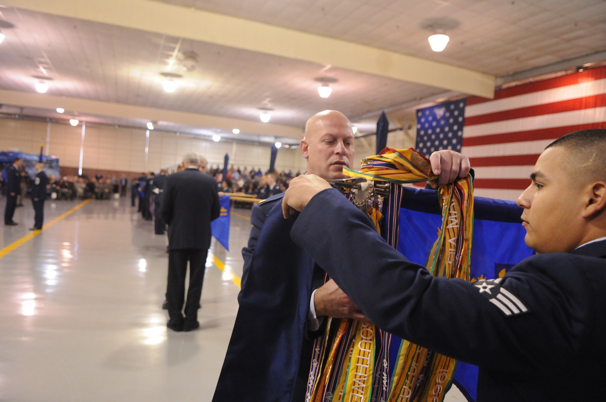 Maj. Frank Hellstern, 902d Security Forces Squadron commander, and Senior Airman Salvador Gutierrez, 902d SFS, furl the 12th Security Forces Squadron flag at an activation ceremony Tuesday in Hangar 4 here where the 12th Mission Support Group inactivated and became the 902d MSG under the 502d Air Base Wing, also known as Joint Base San Antonio. The 12th MSG's four squadrons and three divisions, the 12th Comptroller Squadron and the 12th Flying Training Wing staff agencies also joined the 502d ABW during the ceremony. (U.S. Air Force photo/Rich McFadden)