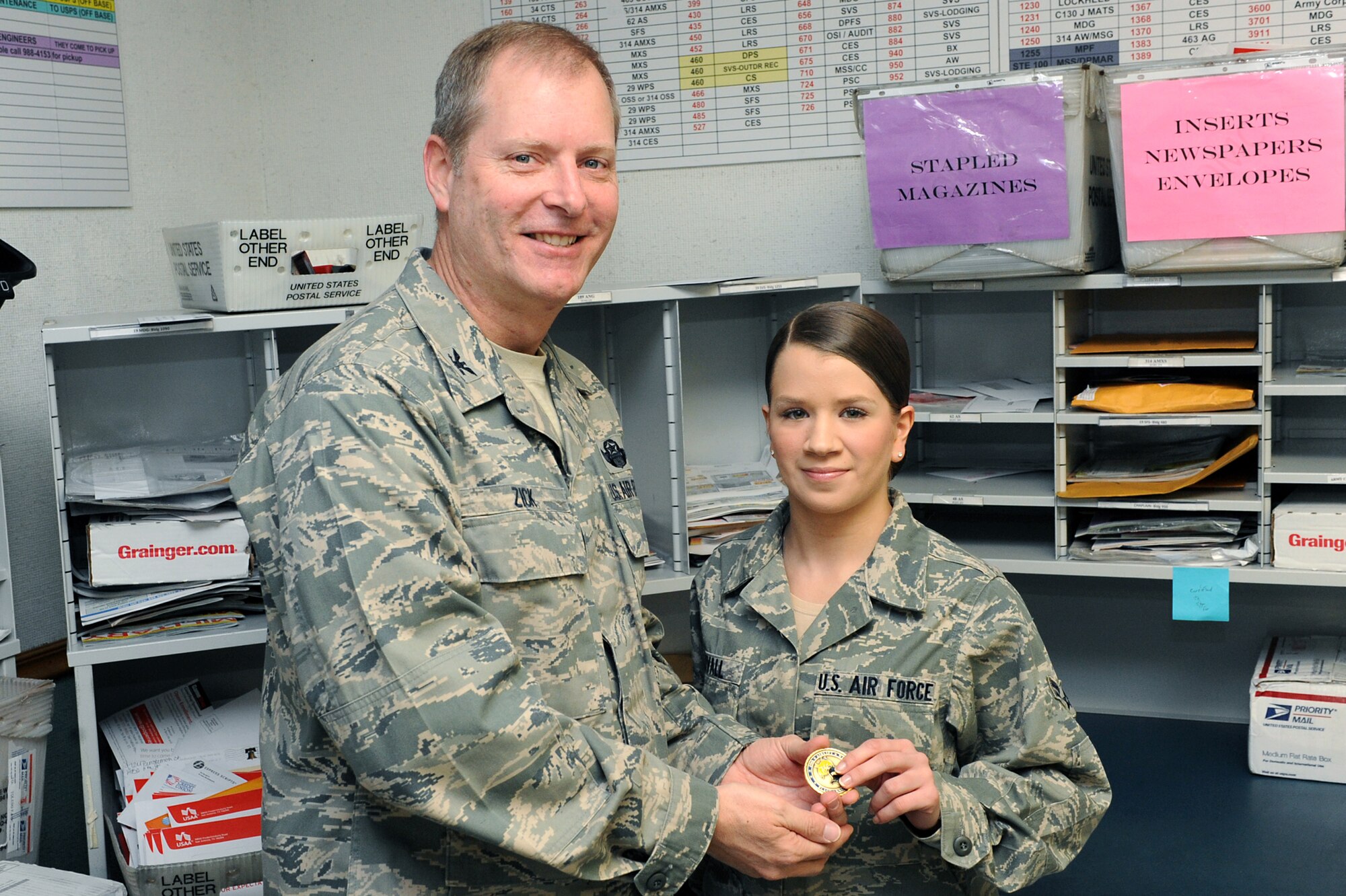 Col. Michael Zick, 19th Airlift Wing vice commander, presents Airman 1st Class Kaelah Ekvall, 19th Communications Squadron knowledge operations apprentice, with a commander’s coin Feb. 2 for being selected Combat Airlifter of the Week. Airman Ekvall was selected for maintaining the office duty schedule while the official mail center NCO-in-charge was attending the NCO Academy. During this time, she trained four new Airmen on ion scanner operations. (U.S. Air Force photo by Senior Airman Ethan Morgan)