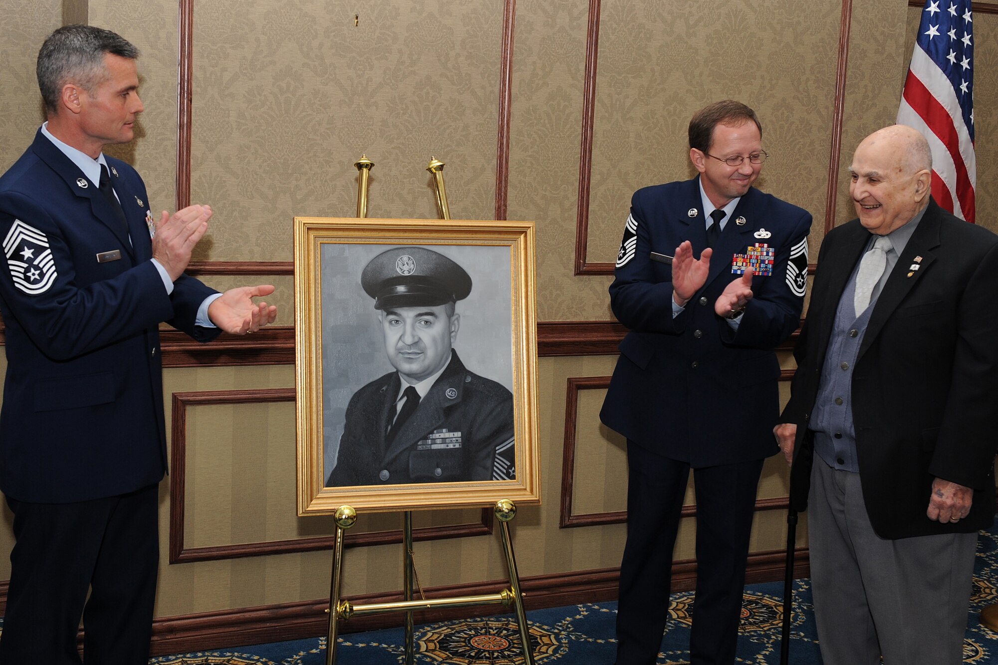 LANGLEY AIR FORCE BASE, Va. -- Chief Master Sgt. Charles Anderson, 633d Air Base Wing command chief, and Chief Master Sgt. Terry Rethamel, Langley Chief's Group president, applaud during the unveiling of retired Chief Master Sgt. Gabriel Christie's portrait Feb. 2. Chief Christie is one of the first 625 Airmen promoted to chief master sergeant, known as "Charter Chiefs."  (U.S. Air Force photo/Senior Airman Zachary Wolf)