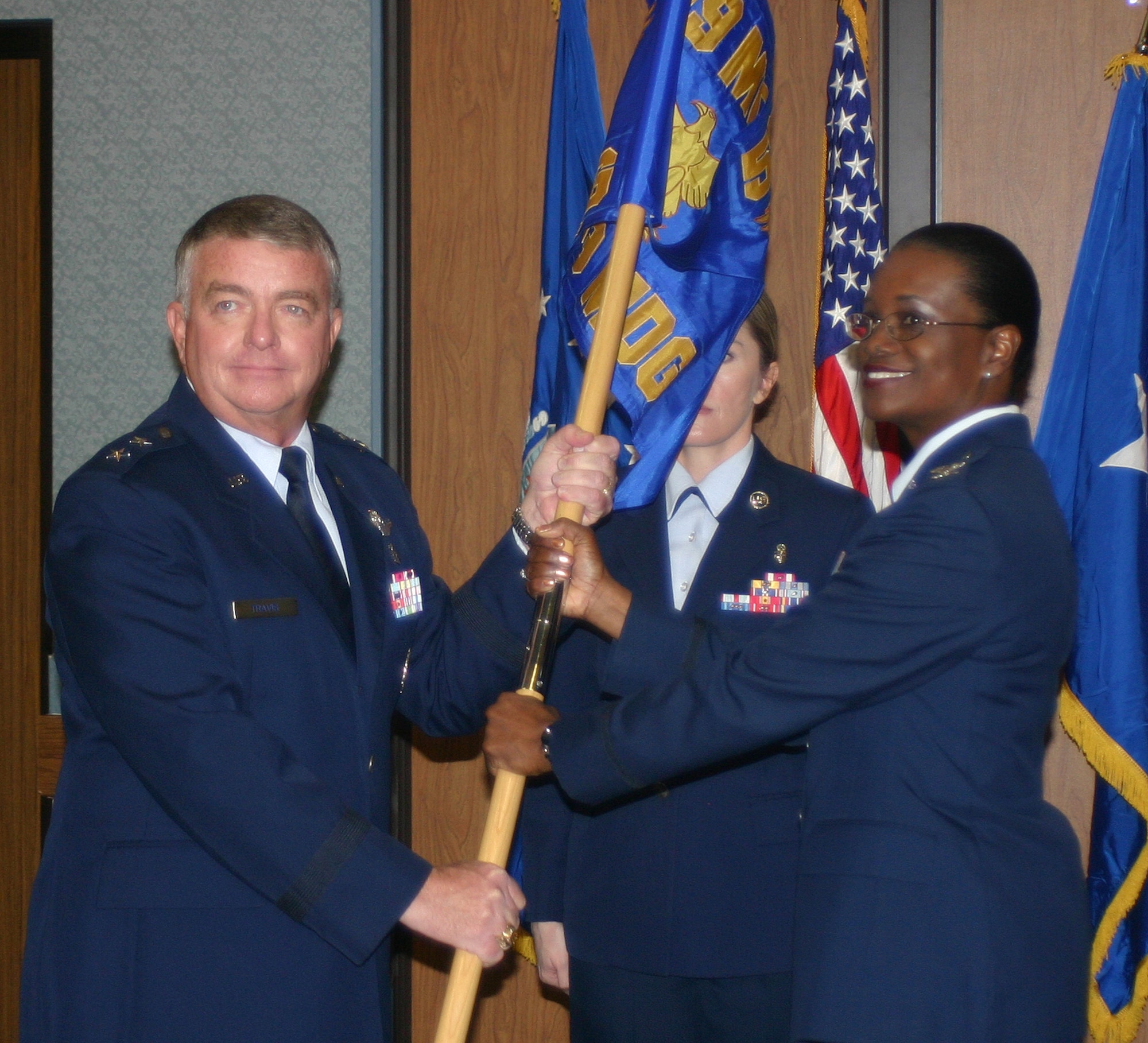Maj. Gen. Tom Travis, 59th Medical Wing commander (left), passes the 359th Medical Group guidon to its commander, Col. Soledad Lindo-Moon, Feb. 1 at Randolph Air Force Base, Texas, during a ceremony that realigned the medical group under the 59th MDW. (U.S. Air Force photo by Sue Campbell)