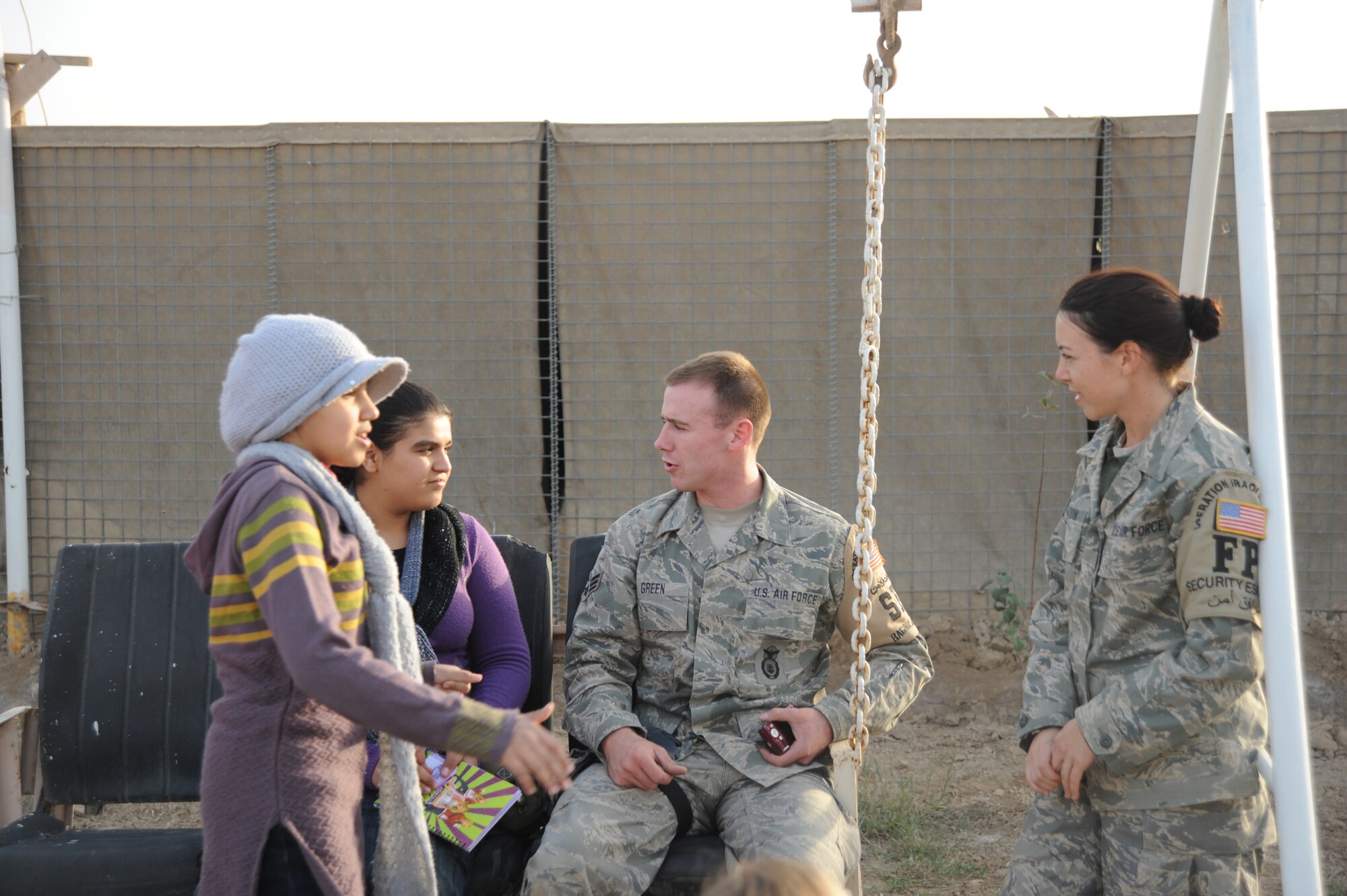Senior Airman Mark Green, 447th Expeditionary Security Forces Squadron, and Staff Sgt. Katrina Hamilton, 447th Expeditionary Civil Engineer Squadron,  talk with a group of Iraqi children while volunteering with the Good Neighbor Program Jan. 29, 2010. The GNP collects donated items such as toys, clothes, games, school supplies, and other needed items for distribution throughout the Iraqi community. (U.S. Air Force photo/ Senior Airman Eric Summers Jr/ released)