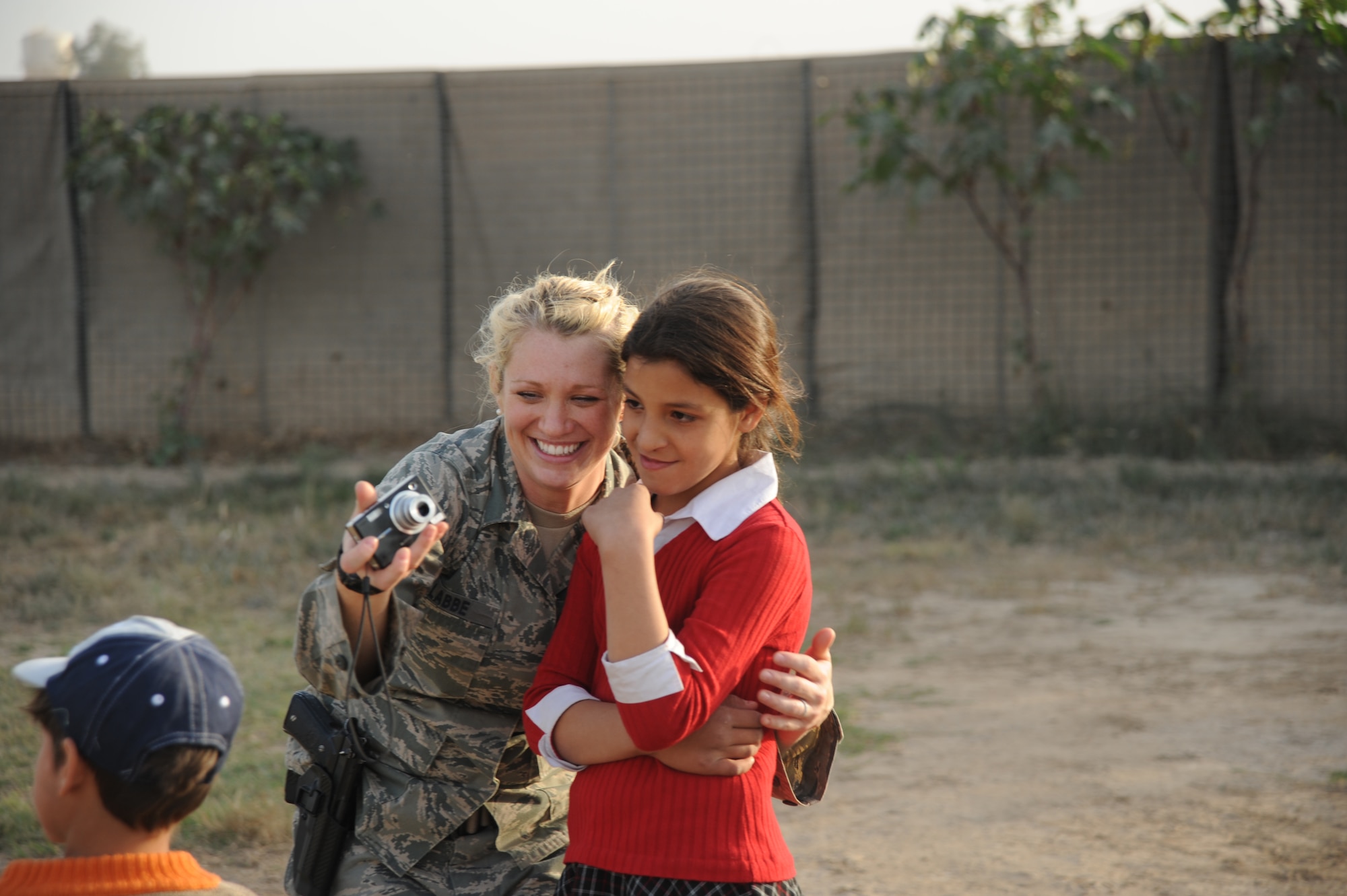Staff Sgt. Tiffany Labbe, Multi-National Forces-Iraq,  displays pictures taken with an Iraqi girl while volunteering with the Good Neighbor Program Jan. 29, 2010. The GNP collects donated items such as toys, clothes, games, school supplies, and other needed items for distribution throughout the Iraqi community. (U.S. Air Force photo/ Senior Airman Eric Summers Jr/ released)
