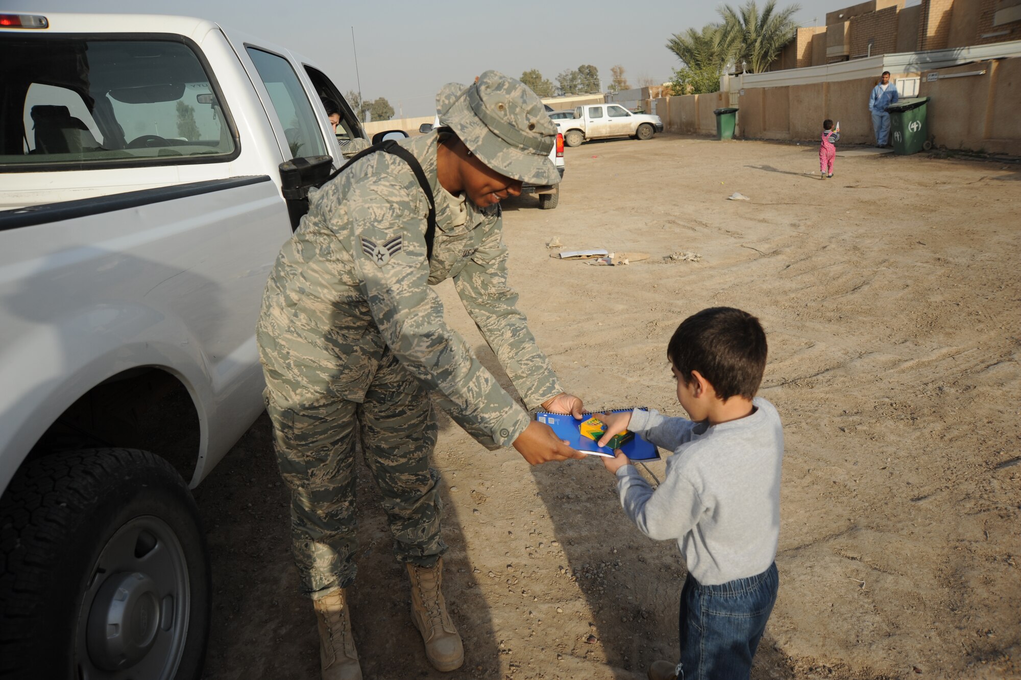 Senior Airman Brena Wilkerson, 447th Expeditionary Communications Squadron, gives an Iraqi boy paper and crayons while volunteering with the Good Neighbor Program Jan. 29, 2010. The GNP collects donated items such as toys, clothes, games, school supplies, and other needed items for distribution throughout the Iraqi community.  (U.S. Air Force photo/ Senior Airman Eric Summers Jr/ released)