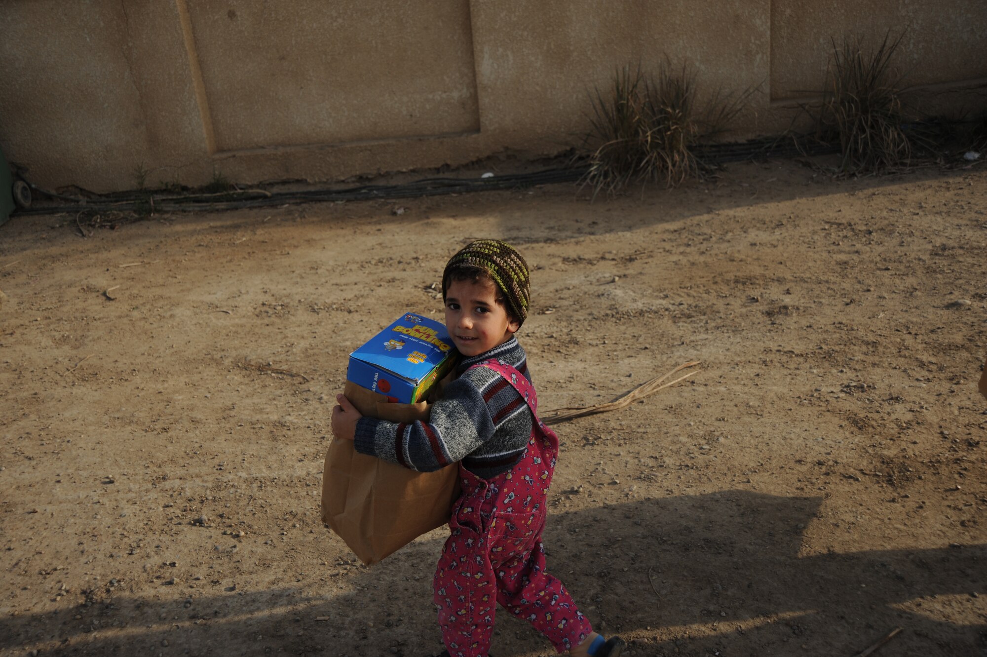 An Iraqi boy carries home a bag of donated games and children toys given as part of the Good Neighbor Program Jan. 29, 2010. The GNP collects donated items such as toys, clothes, games, school supplies, and other needed items for distribution throughout the Iraqi community.  (U.S. Air Force photo/ Senior Airman Eric Summers Jr/ released)