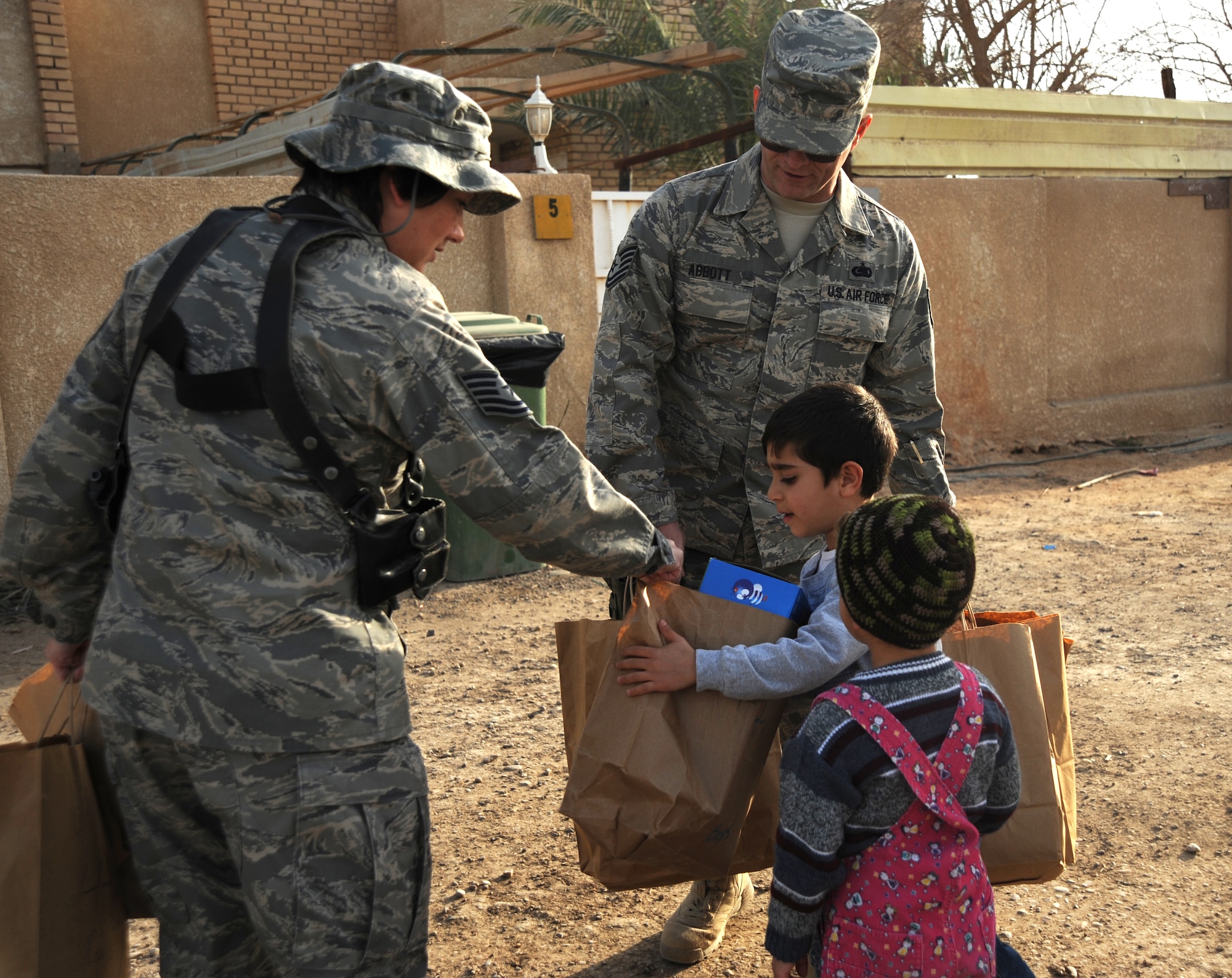 Technical Sgt. Cynthia Callaway, 447th Expeditionary Logistics Squadron, hands a child a big with toys and games while volunteering with the Good Neighbor Program Jan. 29, 2010. The GNP collects donated items such as toys, clothes, games, school supplies, and other needed items for distribution throughout the Iraqi community. (U.S. Air Force photo/ Senior Airman Eric Summers Jr/ released)
