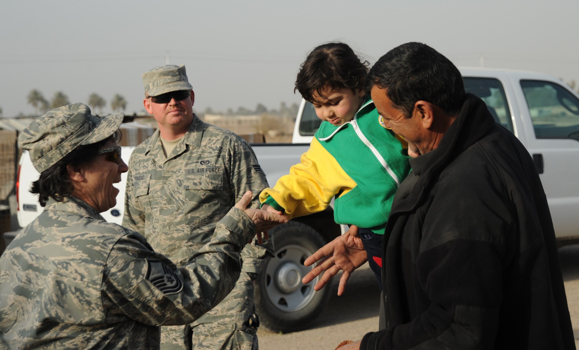 Master Sgt. Margaret Triboletti, 447th Expeditionary Civil Engineer Squadron, hands and Iraqi child a piece of candy while volunteering with the Good Neighbor Program Jan. 29, 2010. The GNP collects donated items such as toys, clothes, games, school supplies, and other needed items for distribution throughout the Iraqi community. (U.S. Air Force photo/ Senior Airman Eric Summers Jr/ released)
