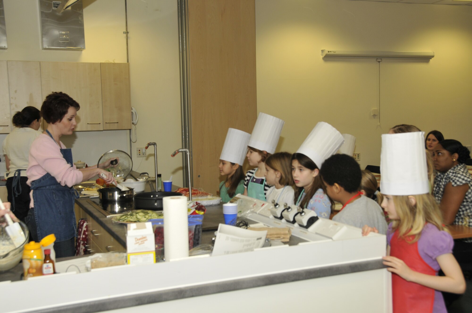 Children surrounded the cooking island to get a better look at the cooking methods in order to learn how they could recreate the same recipe at home. (U.S. Air Force photo/2nd Lt. Ashley Skillman) 
 
