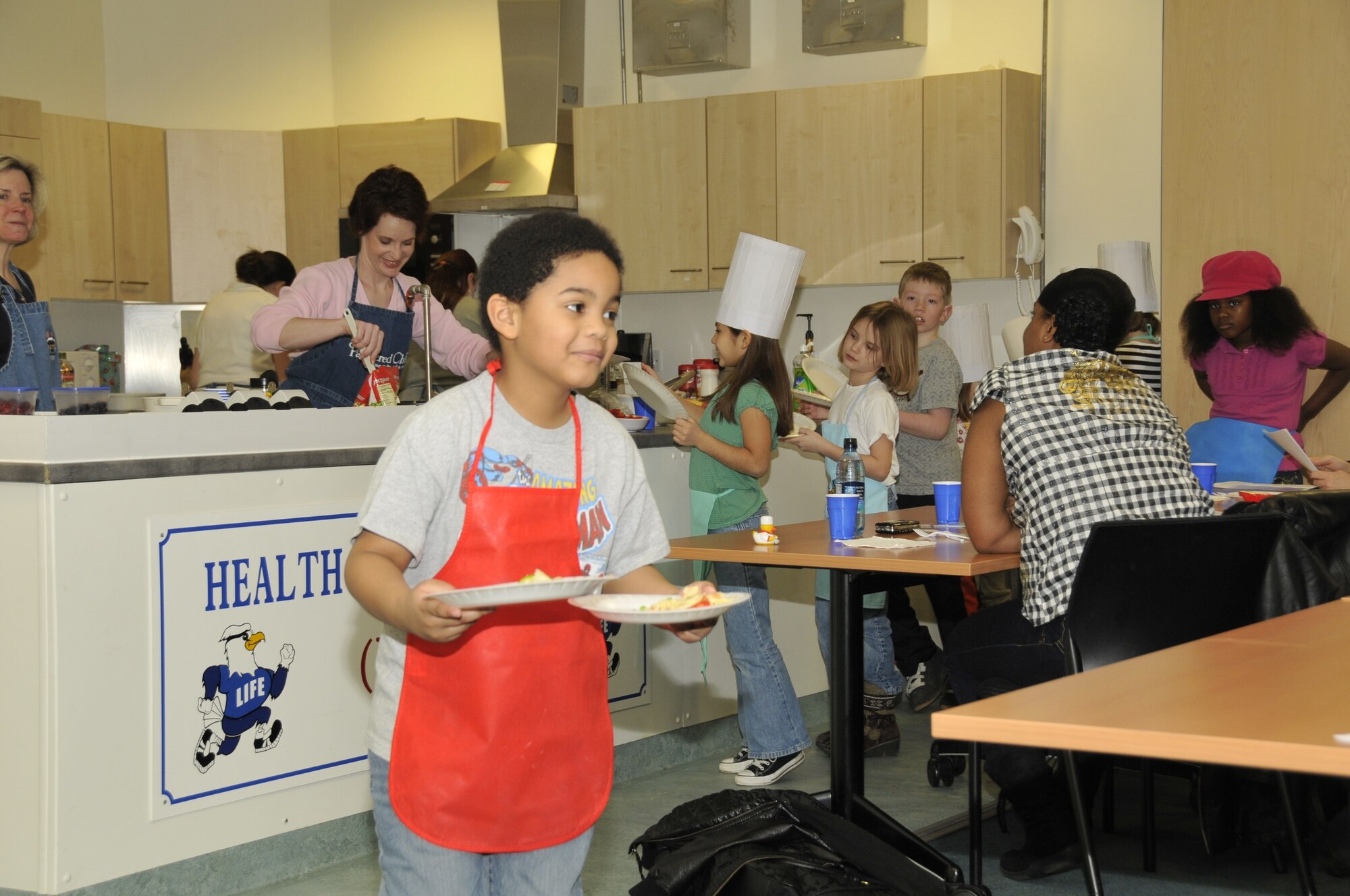 Xavier Martin, 7, son of Staff Sgt. Maybelle Martin, 48th Physical and Occupational Therapy Clinic, brings two plates of stir fry pasta back to the table for him and his mother to share. (U.S. Air Force photo/2nd Lt. Ashley Skillman) 

 
