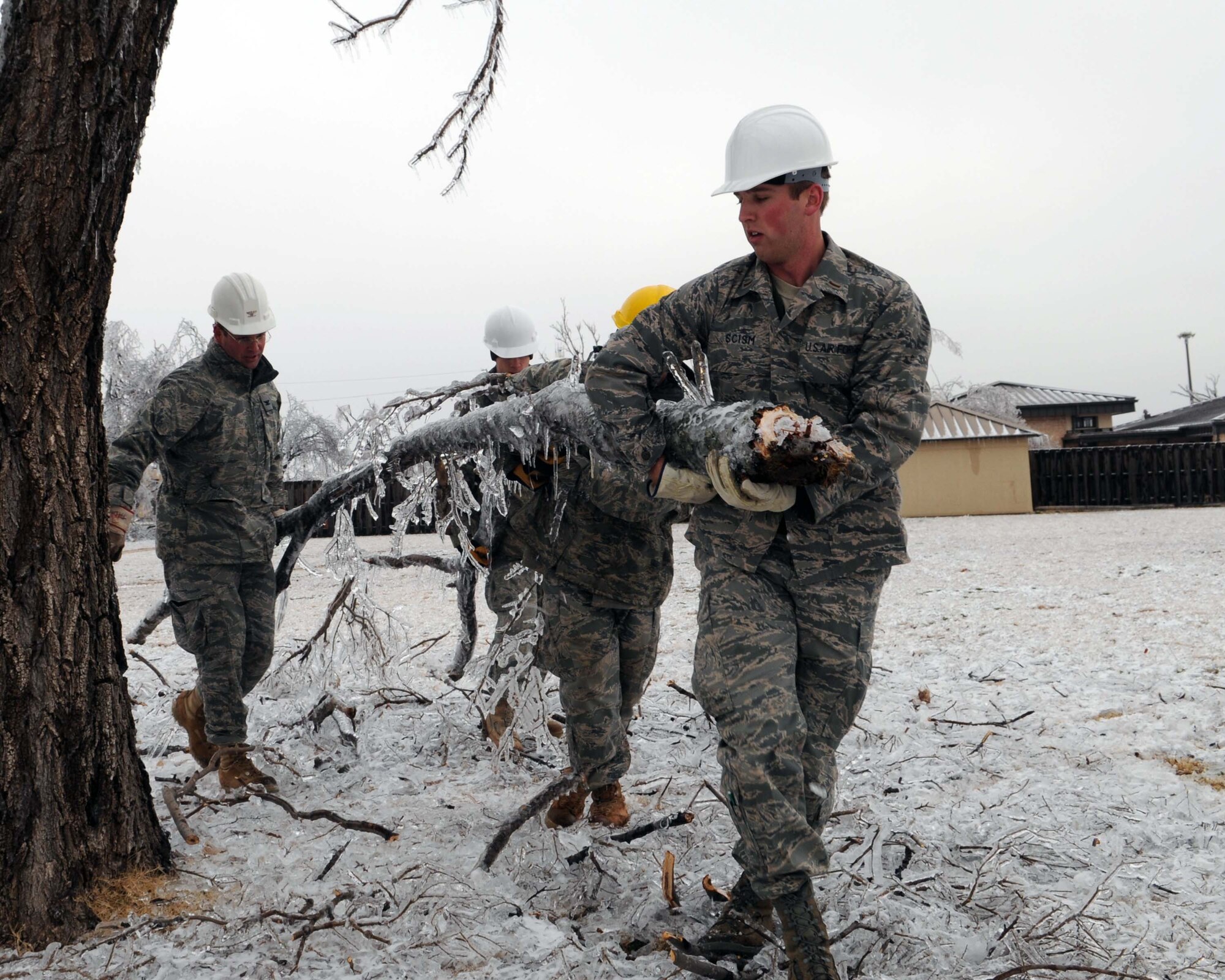 ALTUS AIR FORCE BASE, Okla. -- Senior Airman David Hall, Airman 1st Class Jeremy Winston, and 2nd Lt. Bryan Scism, all with the 97th Civil Engineering Squadron, remove fallen tree limbs Jan. 30. More than 40 people volunteered to clean up the debris that littered the base due to an ice storm that hit Jan. 28. (U.S. Air Force photo/Senior Airman Leandra D. Hernandez)