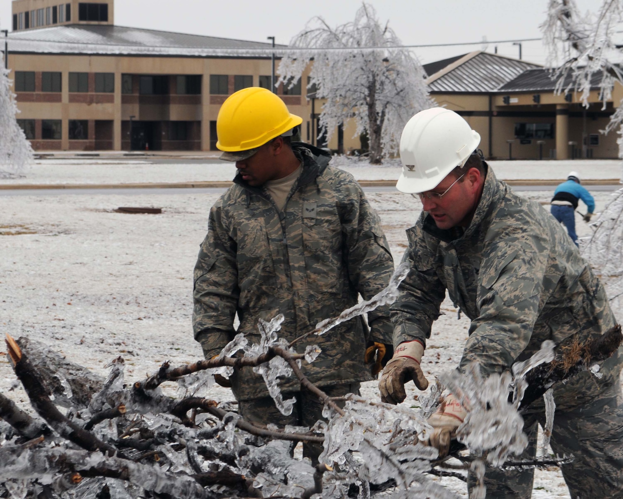 ALTUS AIR FORCE BASE, Okla. -- Col. Ty Thomas, 97th Air Mobility Wing commander, and Airman 1st Class Jeremy Winston, 97th Civil Engineering Squadron, remove fallen tree limbs Jan. 30. More than 40 people volunteered to clean up the debris that littered the base due to an ice storm that hit Jan. 28. (U.S. Air Force photo/Senior Airman Leandra D. Hernandez)