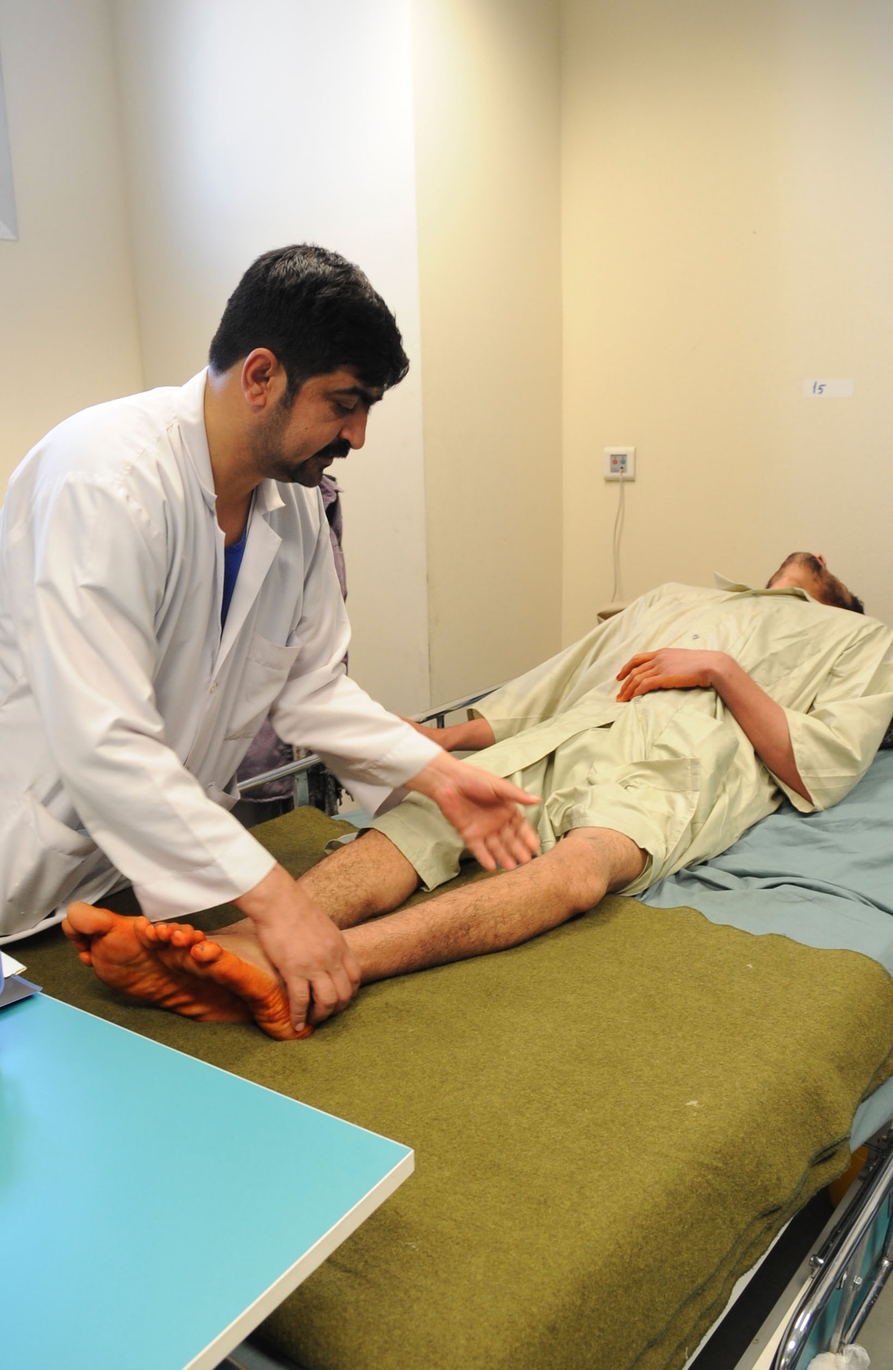 Dr. Shimwari, an Afghan orthopedic doctor at the Kandahar Regional Military Hospital, examines the leg of a patient who had a gunshot wound to his distal thigh during the spring of 2009. The doctor, described as the best Afghan National Army orthopedic doctor, plans to perform an operation on the patient to fix his deformed and shortened leg. (U.S. Air Force photo/Senior Airman Nancy Hooks/Released) 