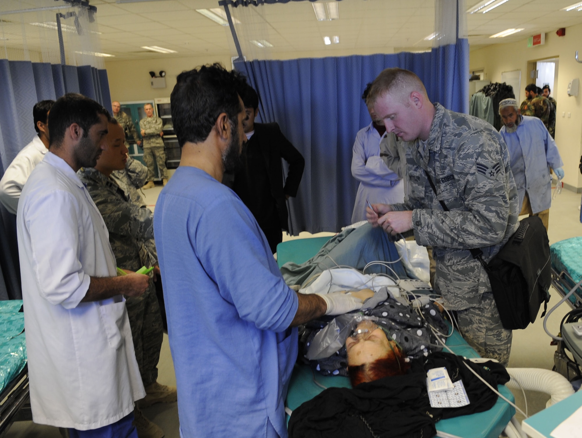 Senior Airman Benjamin Spittler, a mentor for emergency room procedures, advises Afghan medical professionals how on to place EKG, or electrocardiogram, leads on a very lean elderly woman who’d been admitted to the emergency room of the Kandahar Regional Medical Hospital after having a stroke and becoming unconscious after falling Jan. 30, 2010. Airman Spittler is a mentor with the Medical Embedded Training Team for the Kandahar Regional Military Hospital on Camp Hero, Afghanistan. (U.S. Air Force photo/Senior Airman Nancy Hooks/Released)