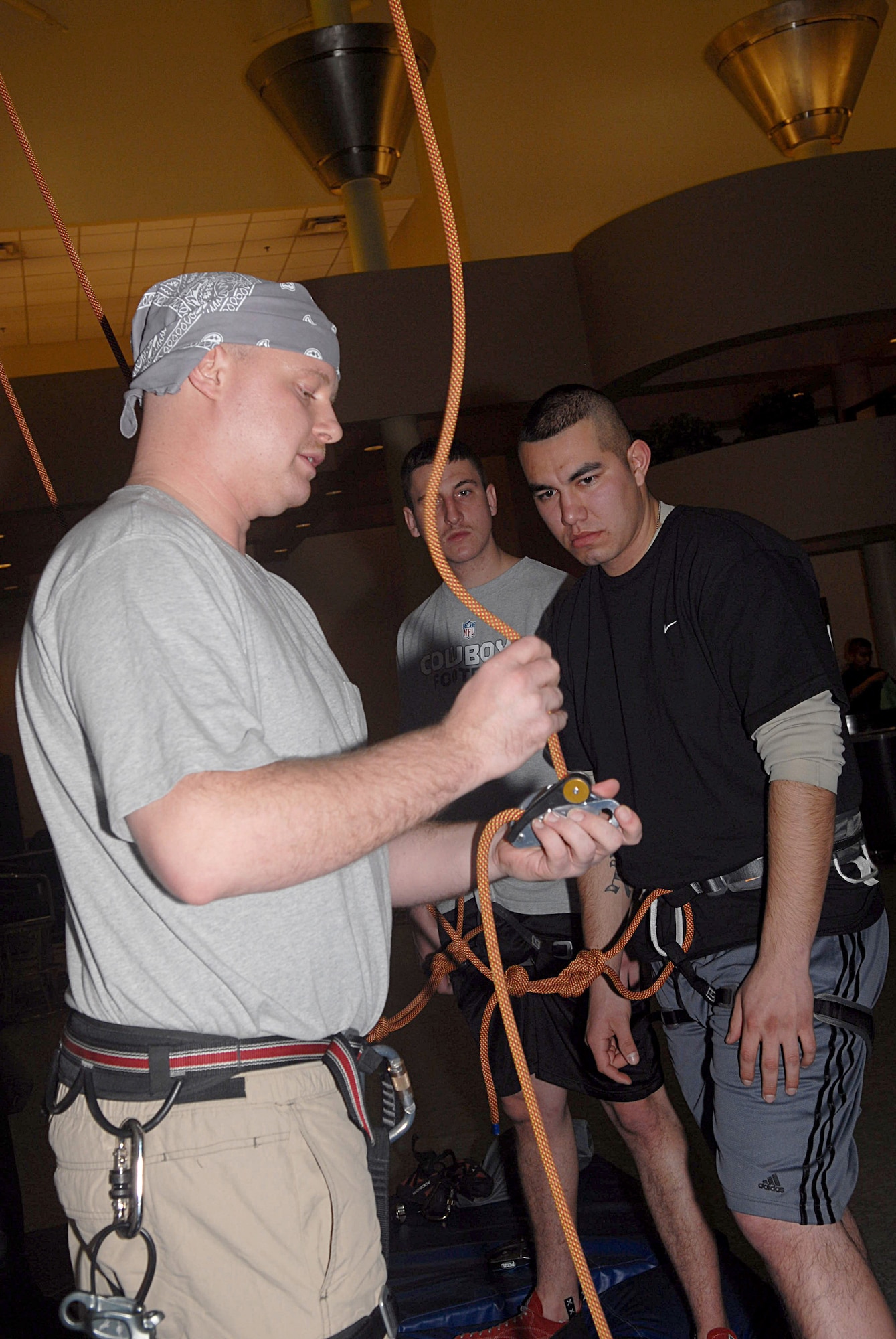KUNSAN AIR BASE, Republic of Korea -- Staff Sgt. John Holwege, 8th Aircraft Maintenance Squadron, instructs Airman 1st Class Jason Early and Senior Airman Alfredo Caballero both from the 391st Aircraft Maintenance Unit on how Gri-Gri functions during a rock wall class at the fitness center Jan. 27. A Gri-Gri is a hand-sized belay device designed to help secure rock climbers by self-locking under a shock load. (U.S. Air Force photo/Senior Airman Roy Lynch)