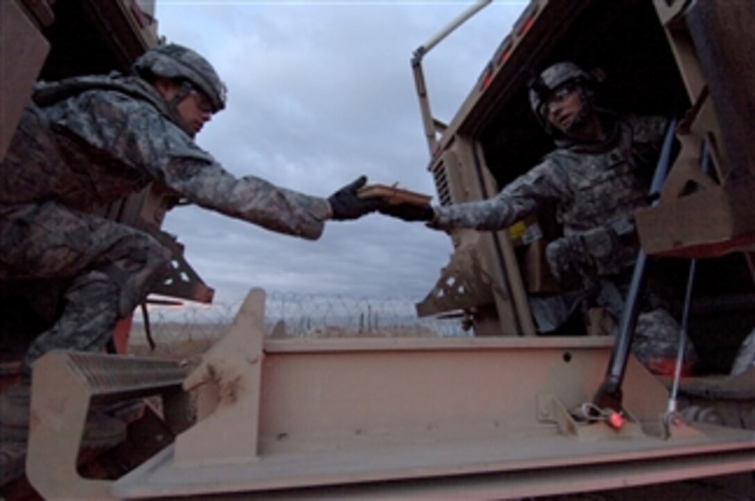 U.S. Army 1st Sgt. Samuel Rapp (right) assigned to 1st Battalion, 64th Armored Regiment, 2nd Brigade Combat Team, 3rd Infantry Division, passes a plate of hot food to another soldier at a combined check point east of Mosul, Iraq, on Jan. 25, 2010.  