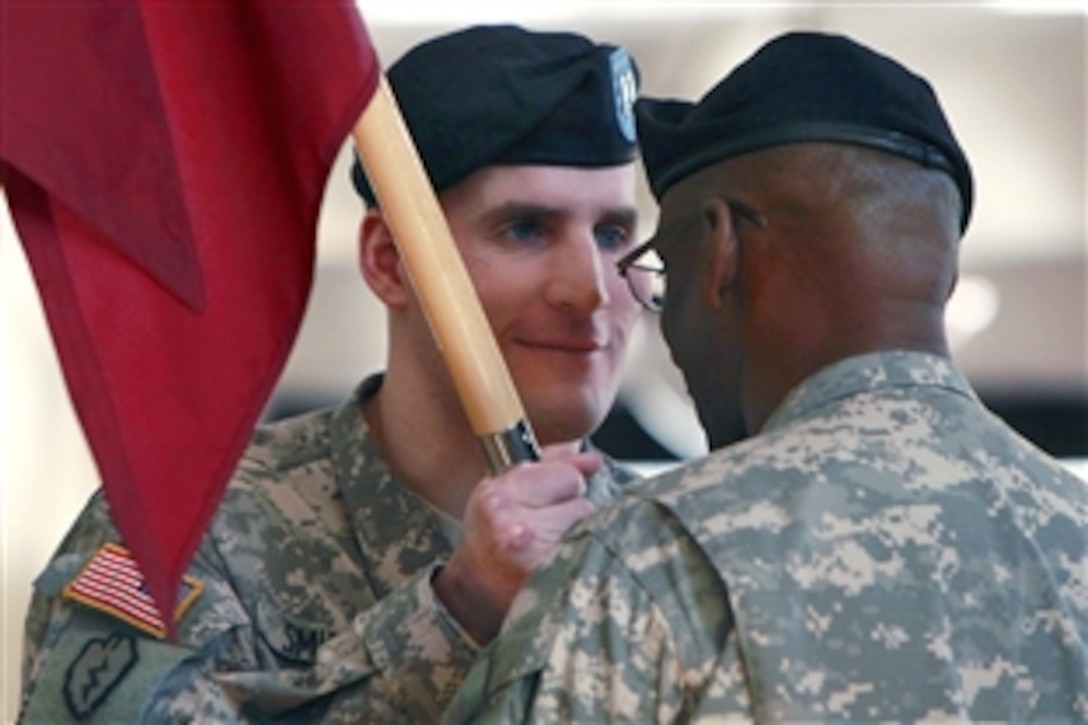 U.S. Army Capt. Scott M. Smiley grins while passing the unit flag back to 1st Sgt. Deon E. Dabrio during the change of command ceremony at the U.S. Army Warrior Transition Unit at West Point, N.Y., Feb 1, 2010. The 2007 Army Times Soldier of the year is the first blind officer and second wounded warrior to hold a position of command.