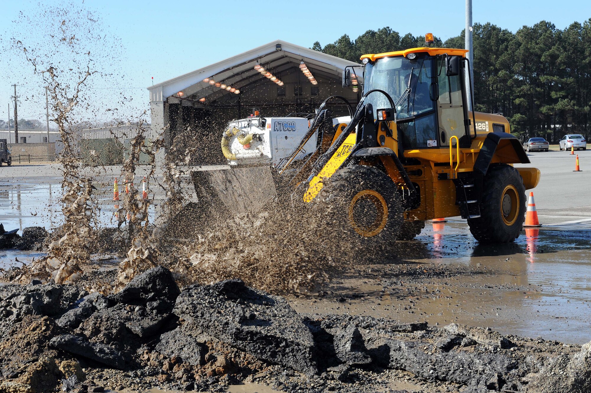 Malcolm Wright, equipment operator from the 4 CES Pavement and Heavy Equipment shop, uses the front end loader to push a 16 foot wide by 16 foot long slab of concrete.  Due to a 10 inch water main break, several 20 inch thick concrete slabs were removed to locate the leak.  The water main pipe fed the fire hydrant system for the aircraft ramp.  (U.S. Air Frce photo by Master Sgt. Brandt Smith)