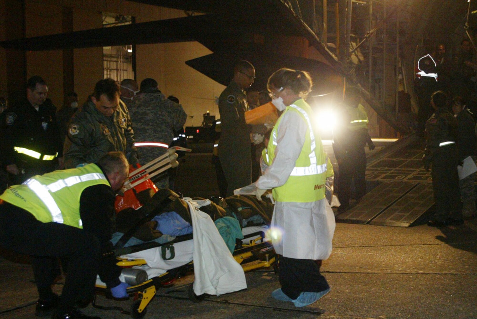 After being airlifted to Dobbins Air Reserve Base, an injured Haitian earthquake victim is rushed to an awaiting ambulance by military and government workers Feb. 2. Half a dozen injured Haitians were flown into Dobbins ARB on a C-130 aircraft late Feb. 2 and transported to local hospitals for urgent care. (U.S. Air Force photo/Don Peek)  

