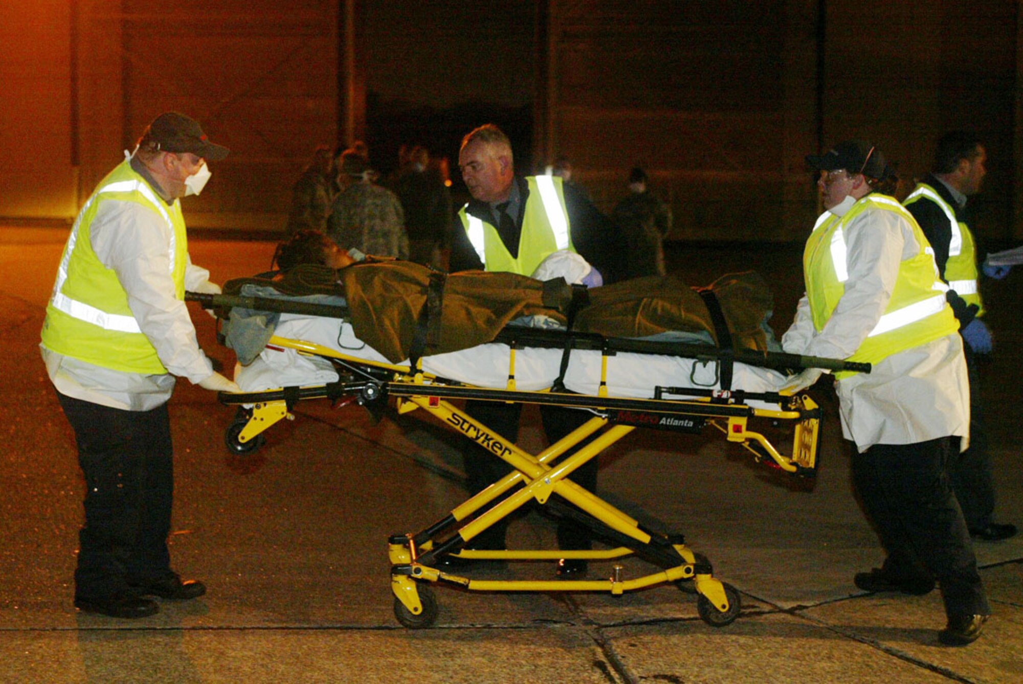 After being airlifted to Dobbins Air Reserve Base, an injured Haitian earthquake victim is rushed to an awaiting ambulance by military and government workers Feb. 2. Half a dozen injured Haitians were flown into Dobbins ARB on a C-130 aircraft late Feb. 2 and transported to local hospitals for urgent care. (U.S. Air Force photo/Don Peek)  

