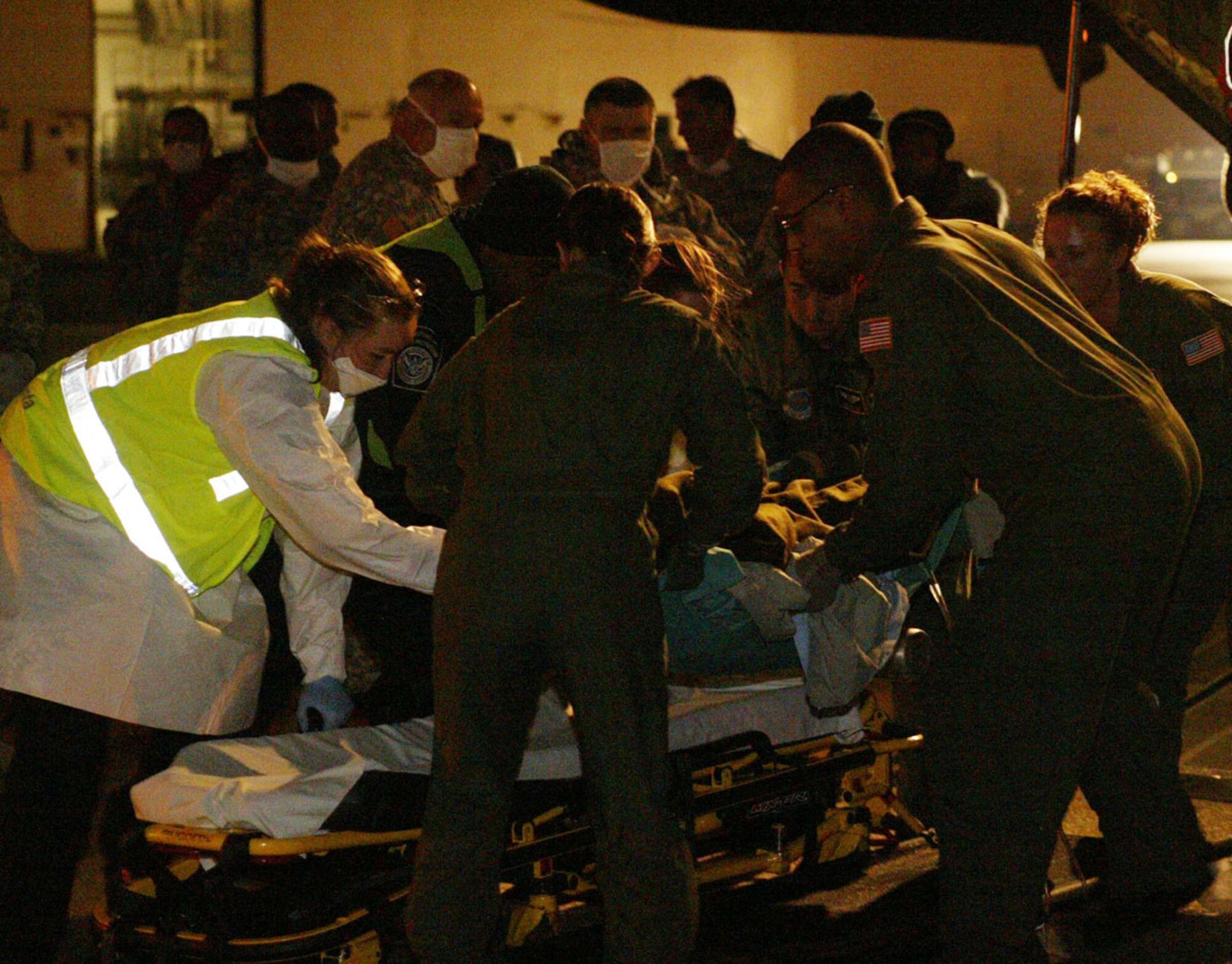After being airlifted to Dobbins Air Reserve Base, an injured Haitian earthquake victim is rushed to an awaiting ambulance by military and government workers Feb. 2. Half a dozen injured Haitians were flown into Dobbins ARB on a C-130 aircraft late Feb. 2 and transported to local hospitals for urgent care. (U.S. Air Force photo/Don Peek)  

