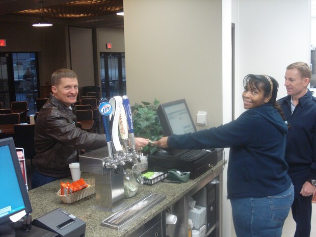 Col. Dave Belote, 99th Air base Wing commander, pays for a coffee, as the first customer of the new golf club house. The new golf club house features new additions to include a special function room. This new room will be able to accommodate 144 players for special events and tournaments. (U.S. Air Force photo by Sharon Pierce)