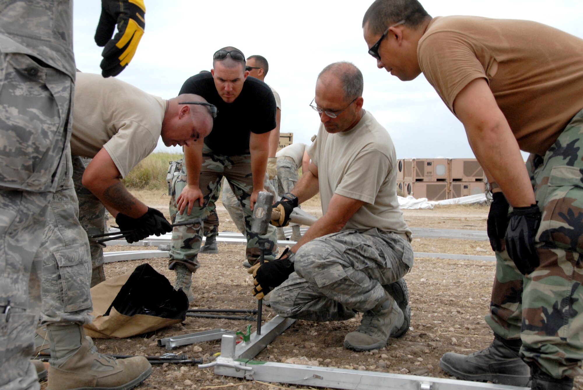 Lt. Col. Mark Green (center) demonstrates the proper technique for anchoring an Expeditionary Medical Support hospital Jan. 25, 2010, in Haiti. Colonel Green is the commander of the Kansas Air National Guard's 190th Civil Engineering Squadron. (U.S. Air Force photo/Tech. Sgt. Emily Alley)