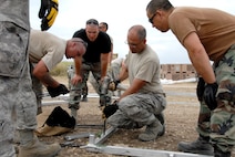 Lt. Col. Mark Green (center) demonstrates the proper technique for anchoring an Expeditionary Medical Support hospital Jan. 25, 2010, in Haiti. Colonel Green is the commander of the Kansas Air National Guard's 190th Civil Engineering Squadron. (U.S. Air Force photo/Tech. Sgt. Emily Alley)