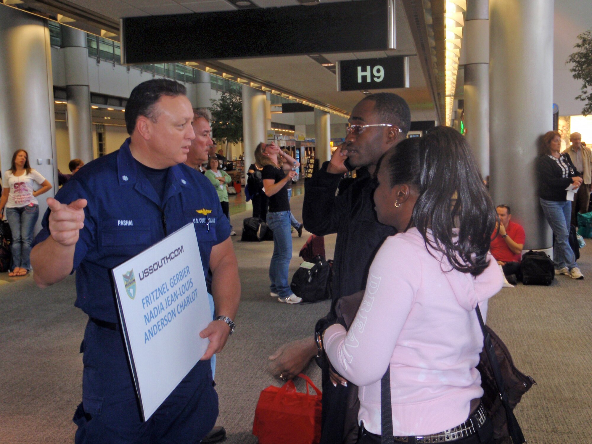 Coast Guard Cmdr. Jeff Pashai greets two Haitian coast guard members Jan. 23, 2010, at the Miami International Airport. The Haitian military members are part of the International Military Exchange Training program and have spent the past six to eight months studying in the U.S. With the help of the U.S. military, seven students reunited with family members in Haiti. Commander Pashai is the U.S. Southern Command Coast Guard TCA liaison. (U.S. Air Force photo/Senior Airman Danielle Grannan)
