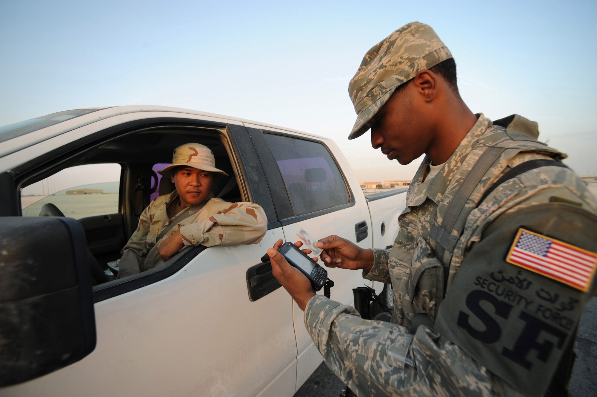 Senior Airman Joseph Wells, 379th Expeditionary Security Forces Squadron security forces journeyman, checks the ID of Navy Seaman Frederick Calija, Combined Task Group 57.1 aviation structural mechanic, at a flightline entry control point at a non-disclosed Southwest Asia location, Feb. 01, 2010. (U.S. Air Force photo by Tech. Sgt. Michelle Larche)[RELEASED]