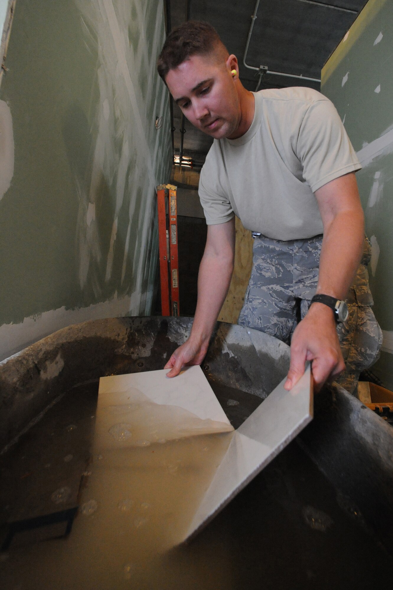Staff Sgt. Jeremiah Messimer, 379th Expeditionary Civil Engineer Squadron structural craftsman, soaks tiles in water before placing them in shower stalls at a bunker cadillac bathroom under construction at a non-disclosed Southwest Asia location, Jan. 27, 2010. (U.S. Air Force photo by Tech. Sgt. Michelle Larche)[RELEASED]