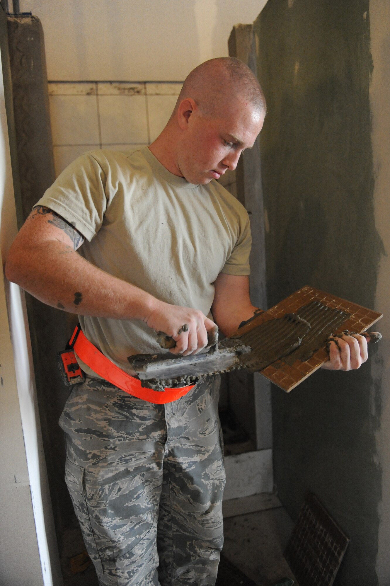 Senior Airman Evan Fronheiser, 379th Expeditionary Civil Engineer Squadron structural journeyman, uses a trowel to apply glue to tiles for new bunker cadillac bathrooms at a non-disclosed Southwest Asia location, Feb. 01, 2010. (U.S. Air Force photo by Tech. Sgt. Michelle Larche)[RELEASED]