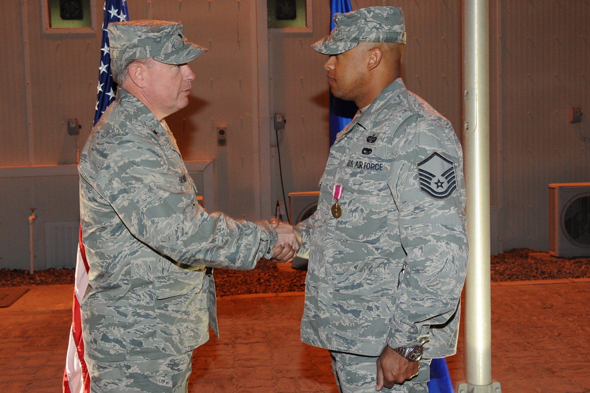 Master Sgt. Shawn Brooks,380th Air Expeditionary Wing law office superintendent and non-commissioned officer in charge of honor guard, receives the wing coin  during his awards presentation from Brig. Gen. Bryan Benson, 380th AEW commander, at an undisclosed location in Southwest Asia on Feb. 2, 2010 Sergeant Brooks has been the NCOIC of the honor guard since November and received a  flag, wing coin and chief's coin for his dedication and service to the honor guard and within the legal office. Sergeant Brooks hails from Brooklyn, N.Y. and is deployed from Air education Training Command Headquarters legal office Randolph Air Force Base, Texas, where he is the law office manager. (U.S. Air Force photo/Senior Airman Jenifer H. Calhoun/Released)

