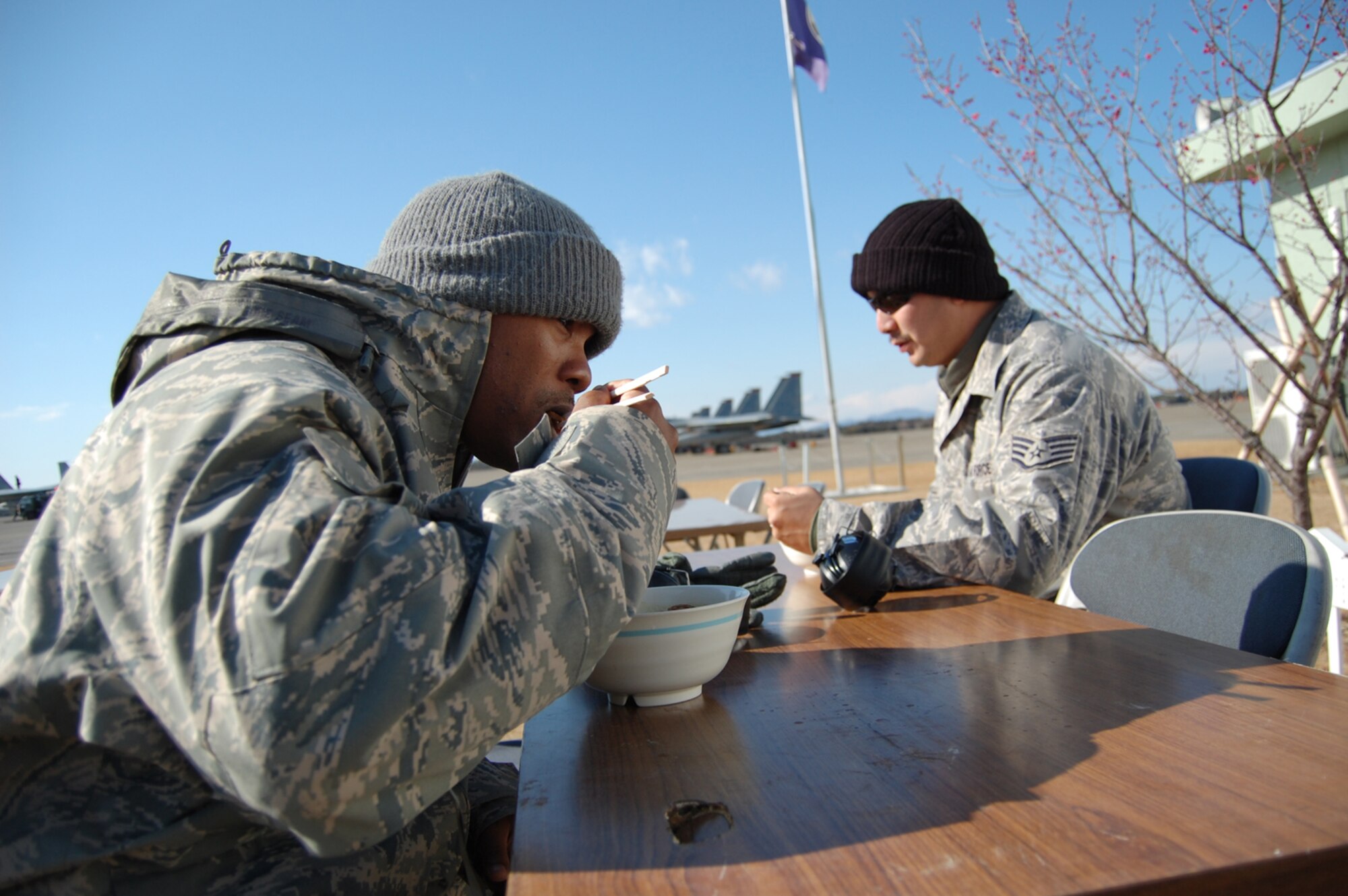 Staff Sgt. Horace Winfrey, 18th Component Maintenance Squadron (left) and Staff Sgt. Wilson Souza have a flightline lunch Feb. 3 at Hyakuri Air Base, Japan. The Japanese NCOs made curry udon for the entire flightline and treated American Airmen to the lunch. The Japan Air Self Defense Force is hosting members of the 18th Wing as part of an aviation training relocation. (U.S. Air Force photo / 1st Lt. Bryan Bouchard)