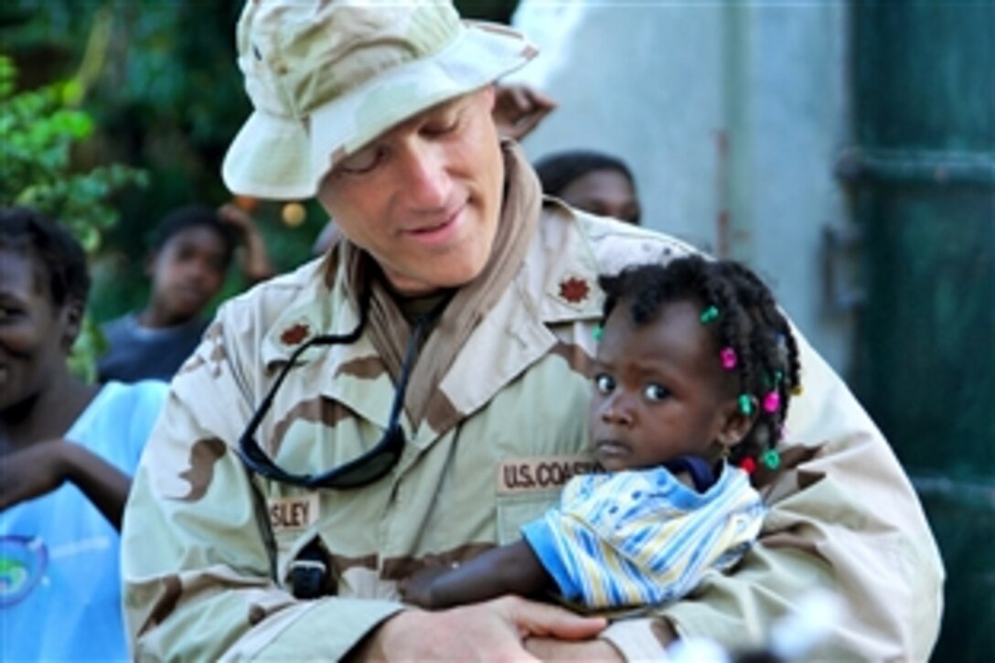 U.S. Coast Guard Lt. Cmdr. Jay Wamsley holds a Haitian toddler during a humanitarian visit to one of many small villages outside Port-Au-Prince, Haiti, Feb. 2, 2010. Wamsley, an environmental health and safety officer, is temporarily assigned to Port Security Unit 307.