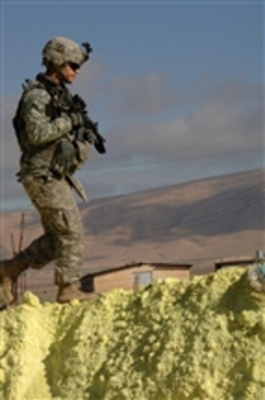 U.S. Army Cpl. Alexander Marston, assigned to Delta Company, 1st Battalion, 64th Armored Regiment, 2nd Brigade Combat Team, 3rd Infantry Division, walks along a mound of sulfur at a storage facility in Keramlais north of Qara Qosh, Iraq, on Jan. 26, 2010.  