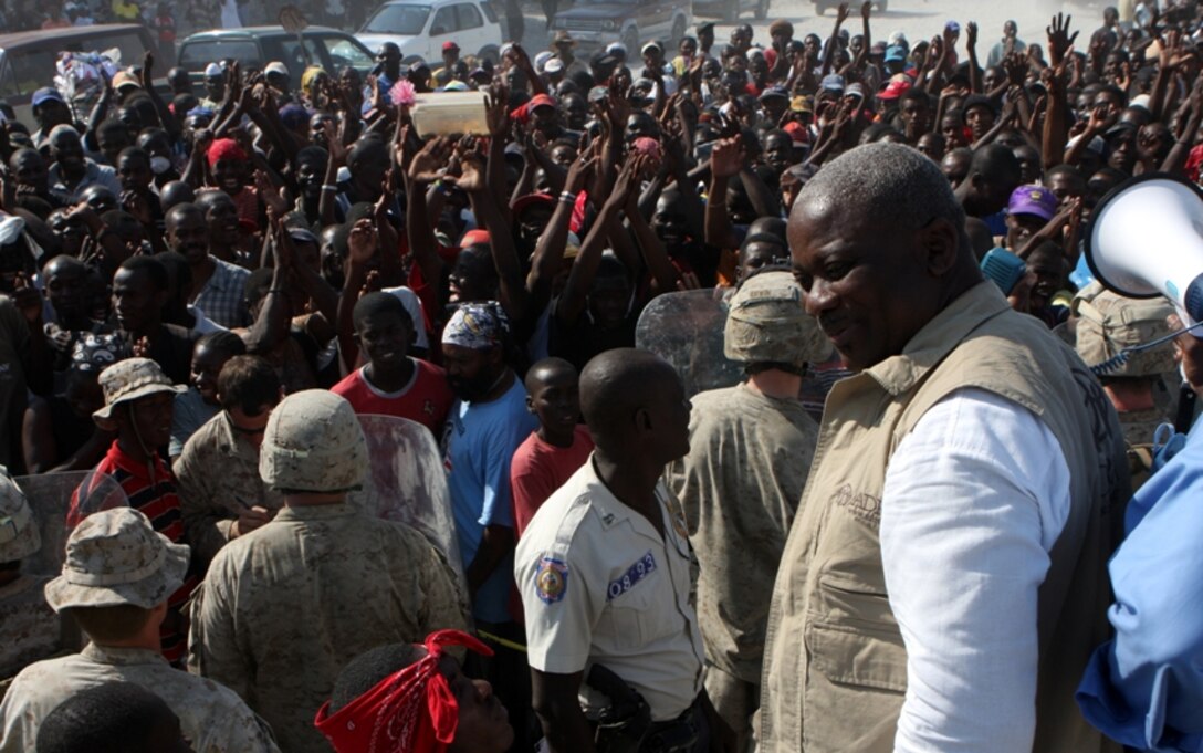 Haitians erupt in praise as Fritz Bissereth, Haiti director, Adventist Development and Relief Agency, announces the relief his organization continues to provide in Carrefour Haiti, as a Marine shield team from Weapons Company, Battalion Landing Team 1st Battalion, 9th Marine Regiment, 24th Marine Expeditionary Unit, safely holds a crowd of Haitians in place outside a food distribution site Feb. 3.  24th MEU Marines provided security alongside the Sri Lankan Army with United Nations at an ADRA food distribution site.  Marines safely managed Haitian crowds as ADRA volunteers quickly and efficiently dispense relief supplies.  24th MEU is among the most versatile military units in the world and ready to perform a gamut of missions in support of Operation Unified Response.  (U.S. Marine Corps photo by Sgt. Alex C. Sauceda)