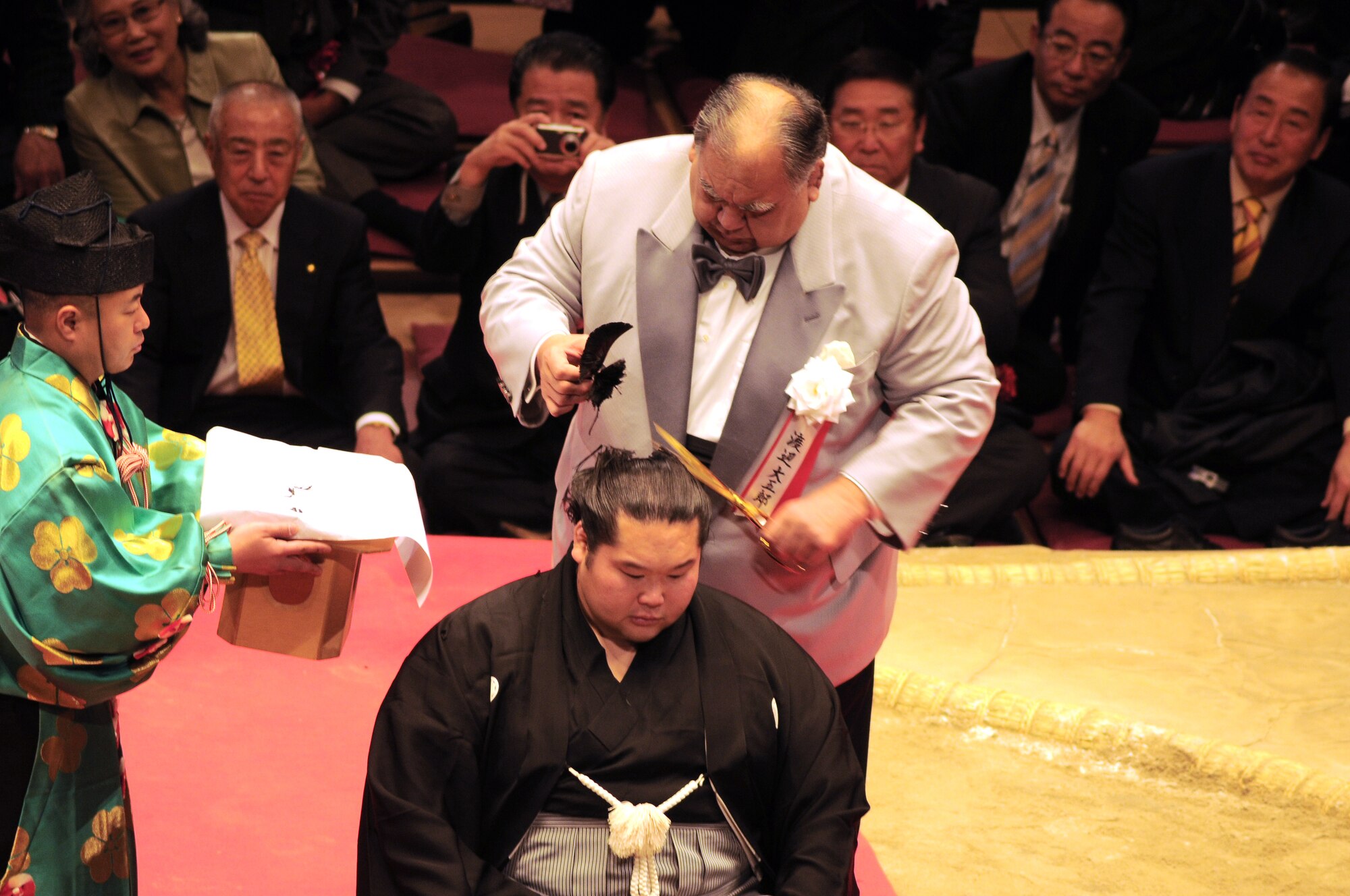 TOKYO -- Mr. Daigora Watanabe, head of Azumazeki-beya, a local Japanese sumo-training center, takes the final snip to Ushiomaru Motoyasu's hair ending his retirement ceremony at the Ryogoku Kokugikan "area" Jan. 31.  Amzumazwki-beya, a local Japanese sumo-training center, invited more than 600 students, parents and teachers from Yokota Air Base to experience this Japanese tradition. (U.S. Air Force photo/Airman 1st Class Katrina Menchaca) 
