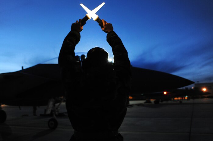 NELLIS AIR FORCE BASE, Nev. -- Senior Airman Patrick Naler, 18th Aircraft Maintenance Squadron, Kadena Air Base, Japan, uses flash lights to communicate to the pilot to hold before launching his F-15 Eagle on a night training mission at Red Flag 10-2, Feb. 2, 2010.  Red Flag is a realistic combat training exercise involving the air forces of the United States and its allies. The exercise is conducted on the 15,000-square-mile Nevada Test and Training Range, north of Las Vegas. (U.S. Air Force photo by Tech. Sgt. Michael R. Holzworth/RELEASED)