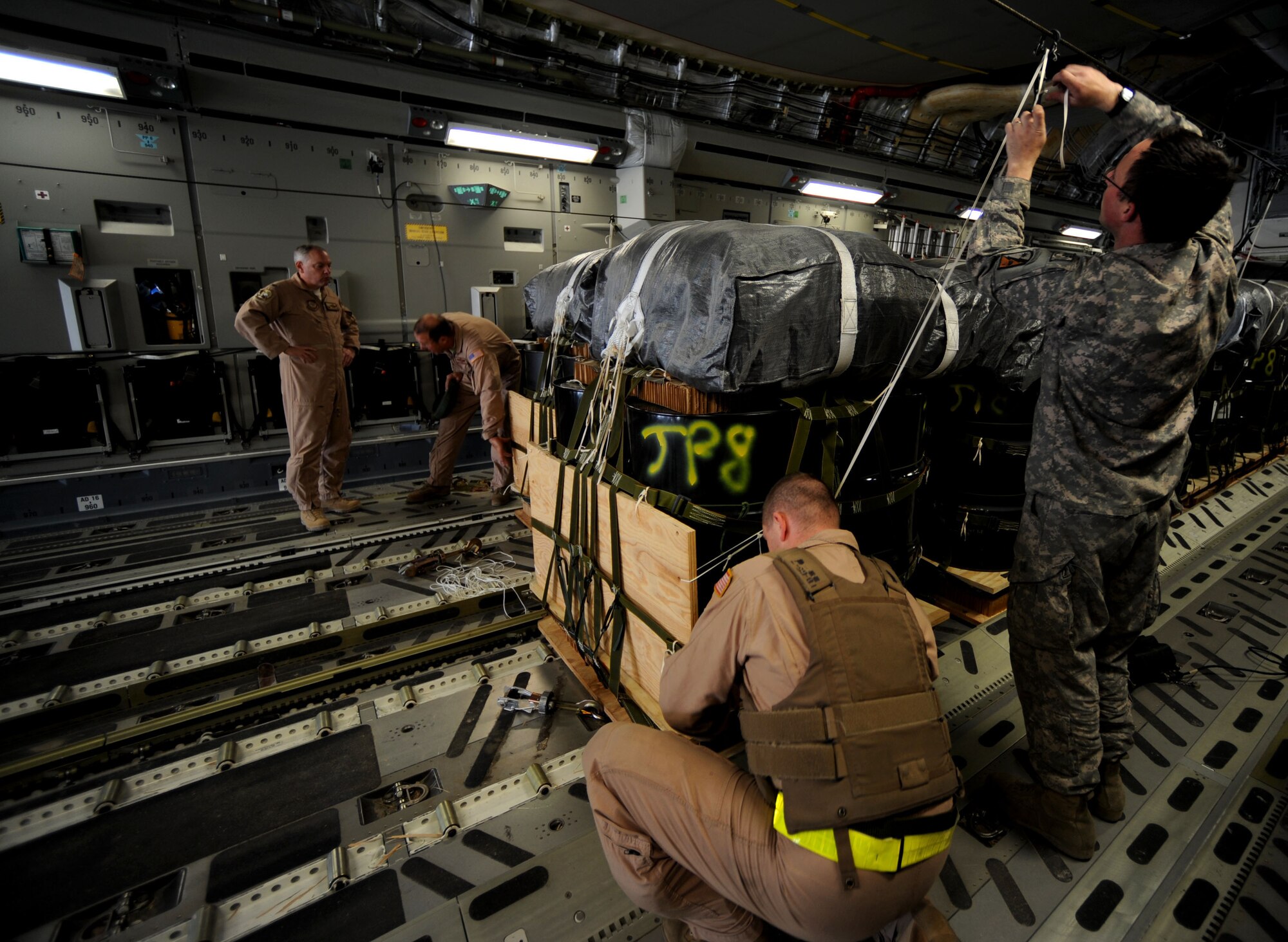U.S. military members strap down containerized delivery system bundles full of supplies onto a C-17 Globemaster III, Feb. 2, 2010, at Bagram Air Base, Afghanistan.  The CDS bundles will be air dropped to ground forces in Afghanistan.  (U.S. Air Force photo/Staff Sgt. Angelita Lawrence/released)