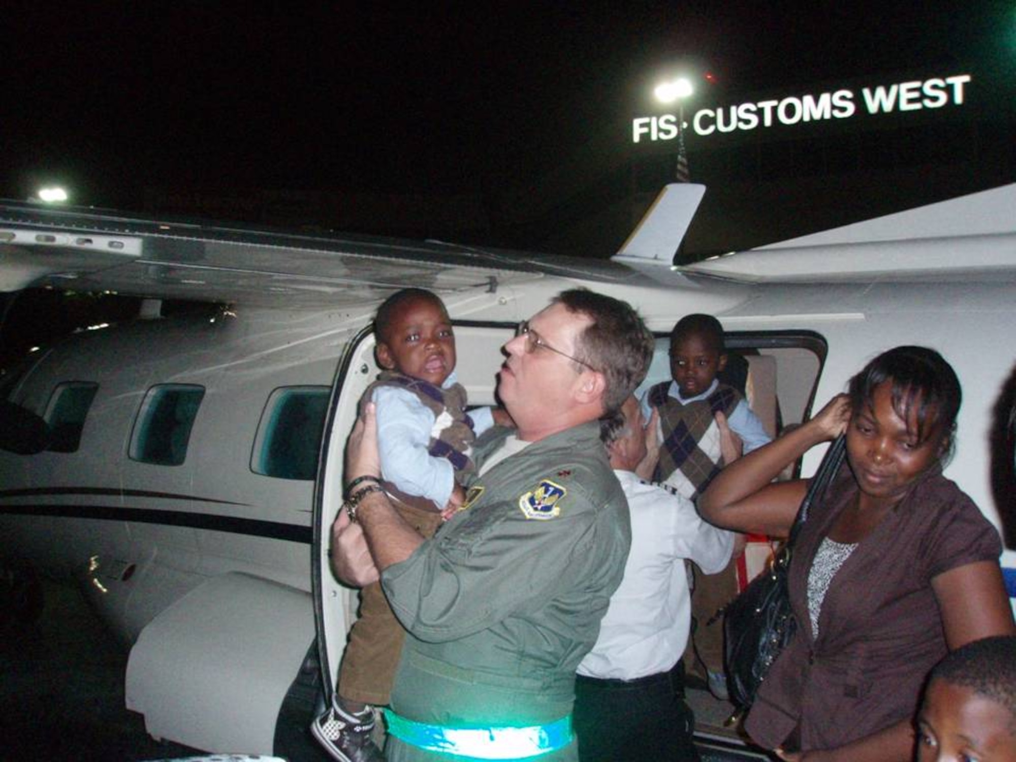 Maj. Chris Reynolds, an Air Forces Northern Emergency Preparedness Liaison Officer, assist Haitians after their arrival at the Ft Lauderdale International Airport on Jan. 22.  EPLOs, trained to respond to natural and manmade disasters in the United States, were on-site to support Haitian earthquake relief efforts.(U.S. Air Force Photo by Lt. Col. Scott Tagg)