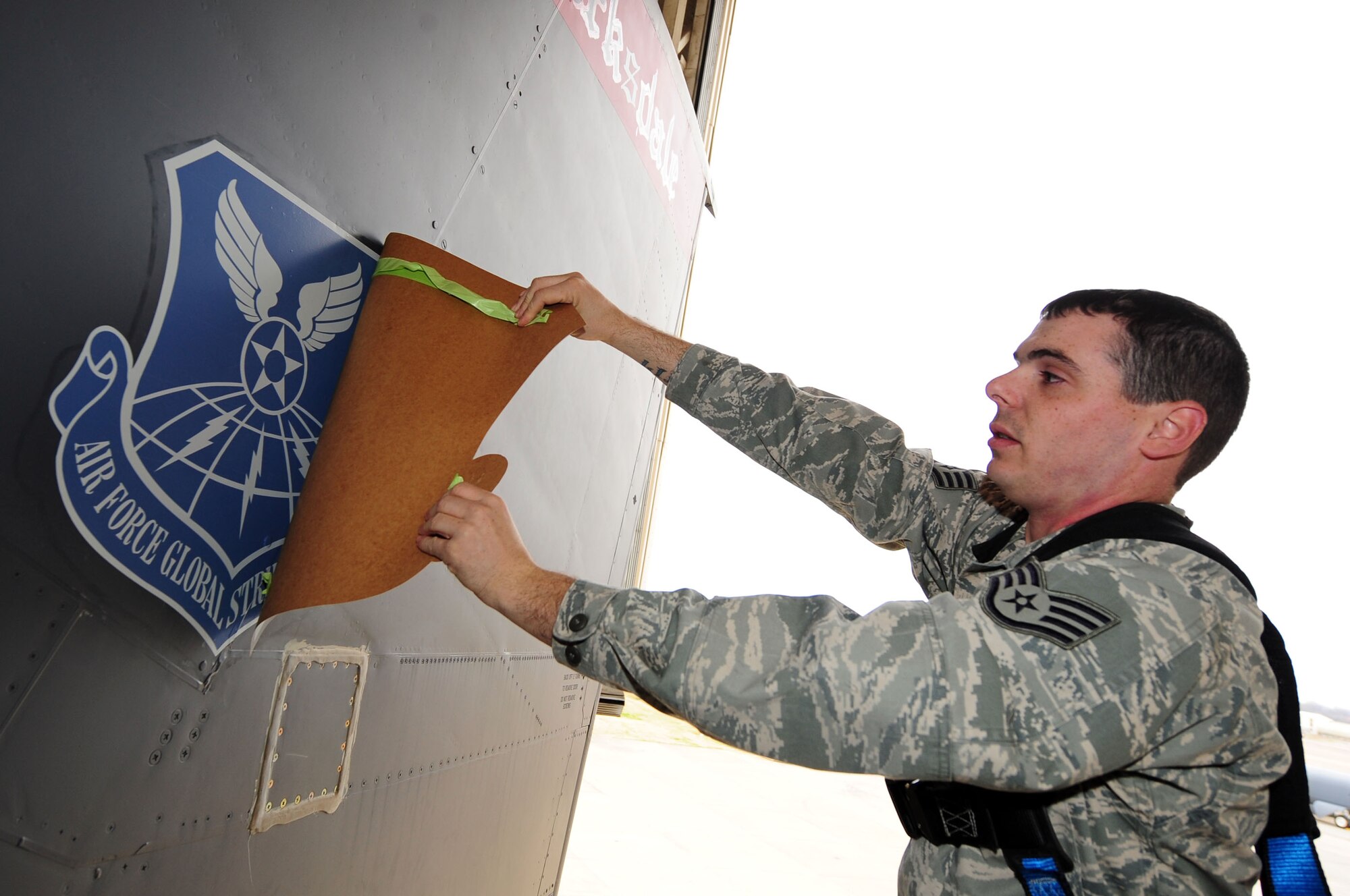 BARKSDALE AIR FORCE BASE, La. -- Staff Sgt. John C. Clark, 2d Maintenance Squadron aircraft structural maintenance technician removes the Air Combat Command shield from the tail of a B-52H Stratofortress to reveal a new Air Force Global Strike Command shield following the wing transition. Switching shields can take up to two hours to accomplish, and the temperature of the aircraft must be higher than 45 degrees for the shield to adhere properly. (U.S. Air Force photo Senior Airman Joanna M. Kresge)